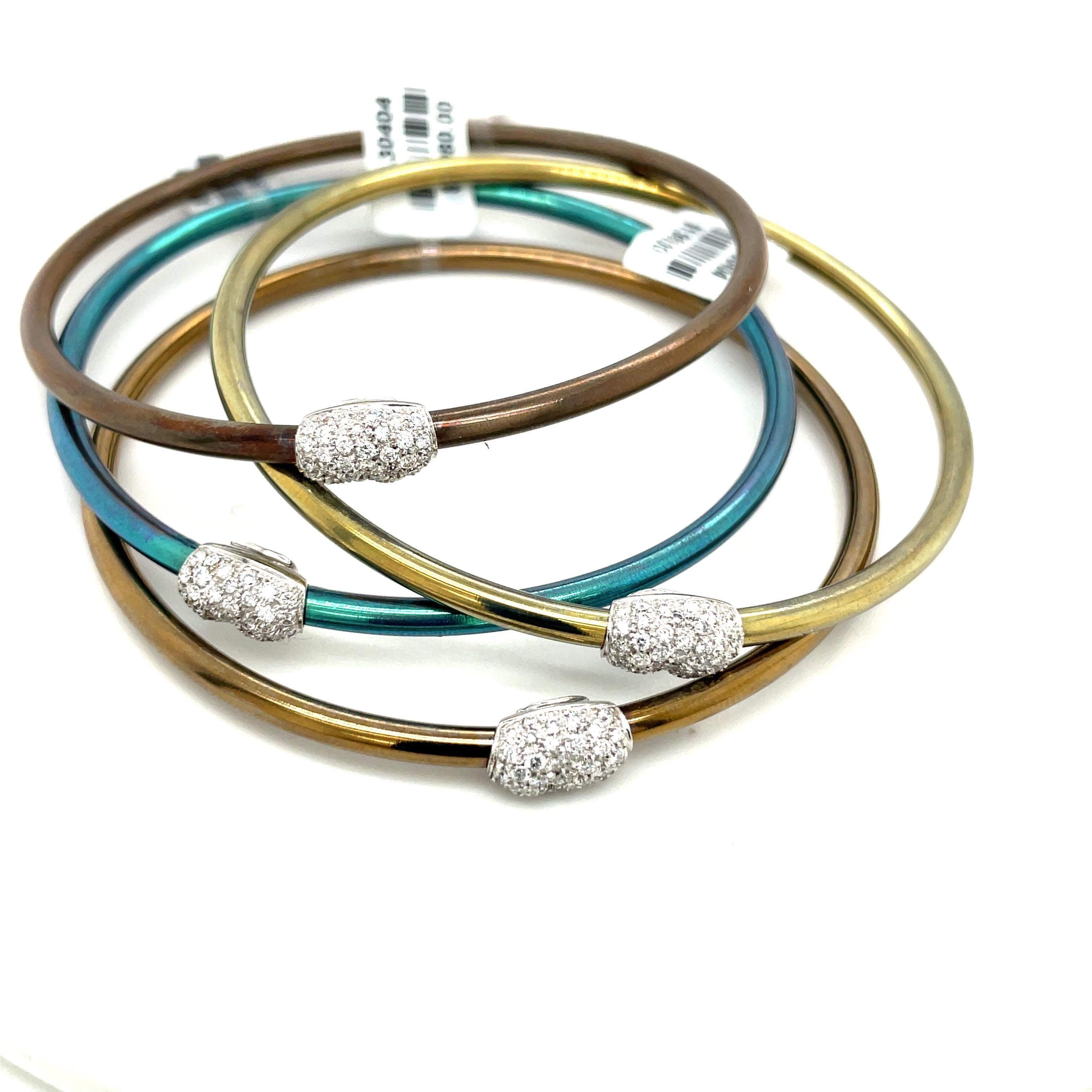 This unique set of bangles is made of colored titanium, which is incredibly lightweight and durable. Accented with and organic 18kt white gold and pave diamond bean, these bangles are sure to spruce up any arm with their charming color and sparkle.