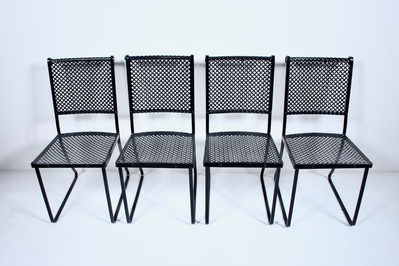 Early set of 4 Troy Sunshade attributed Black Iron & Steel Dining Side Chairs. Featuring sturdy black enameled Iron frameworks, flat Steel strap bases, sturdy criss cross, checkerboard pattern seats, rounded front, slightly curved ergonomic woven