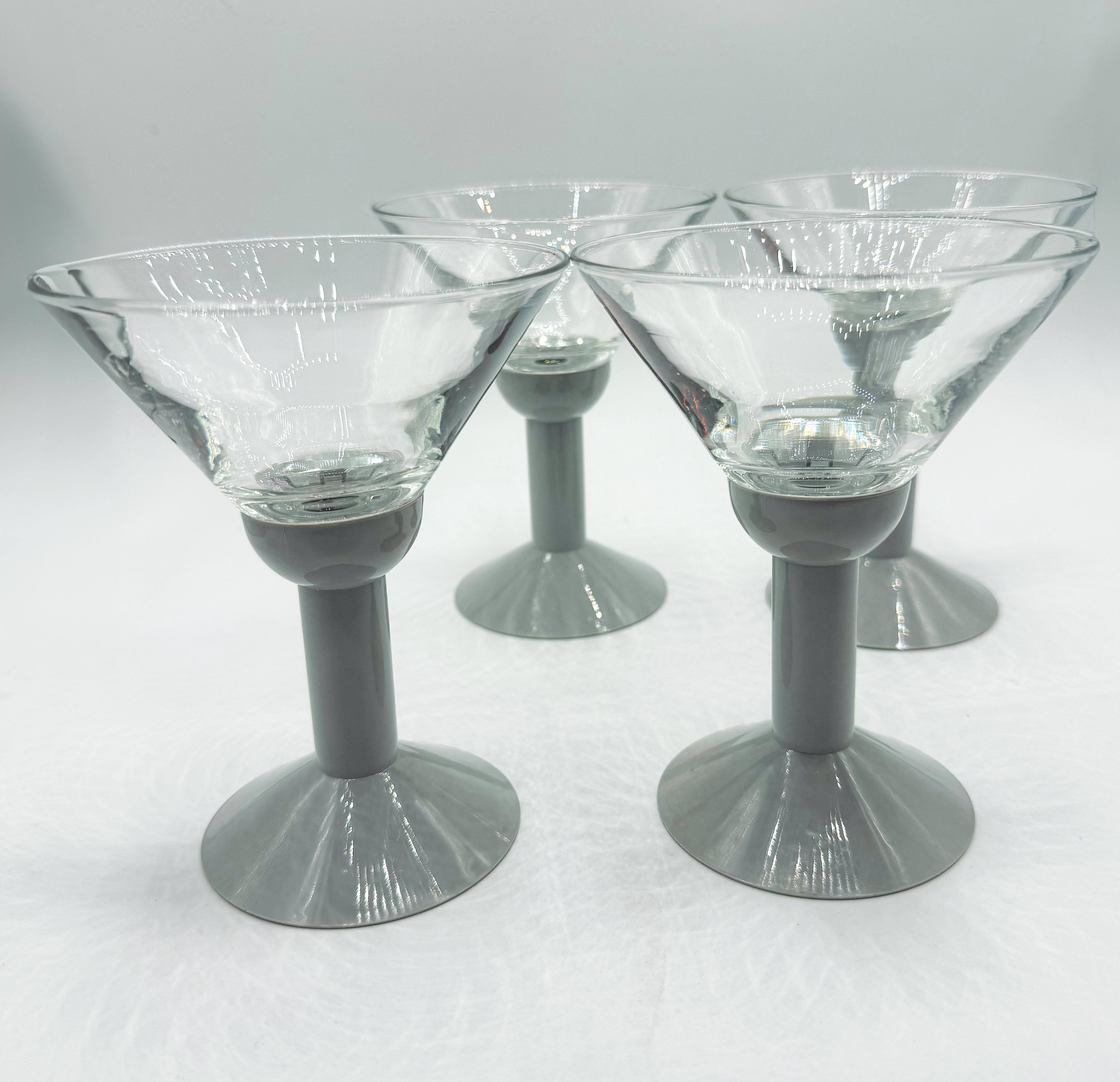 A perfect fusion of form and function, this vintage set of four Bodum Oktett martini glasses from the 1980s brings sleek, modernist design to your barware collection. Each glass features a clear, V-shaped bowl paired with a minimalist grey plastic