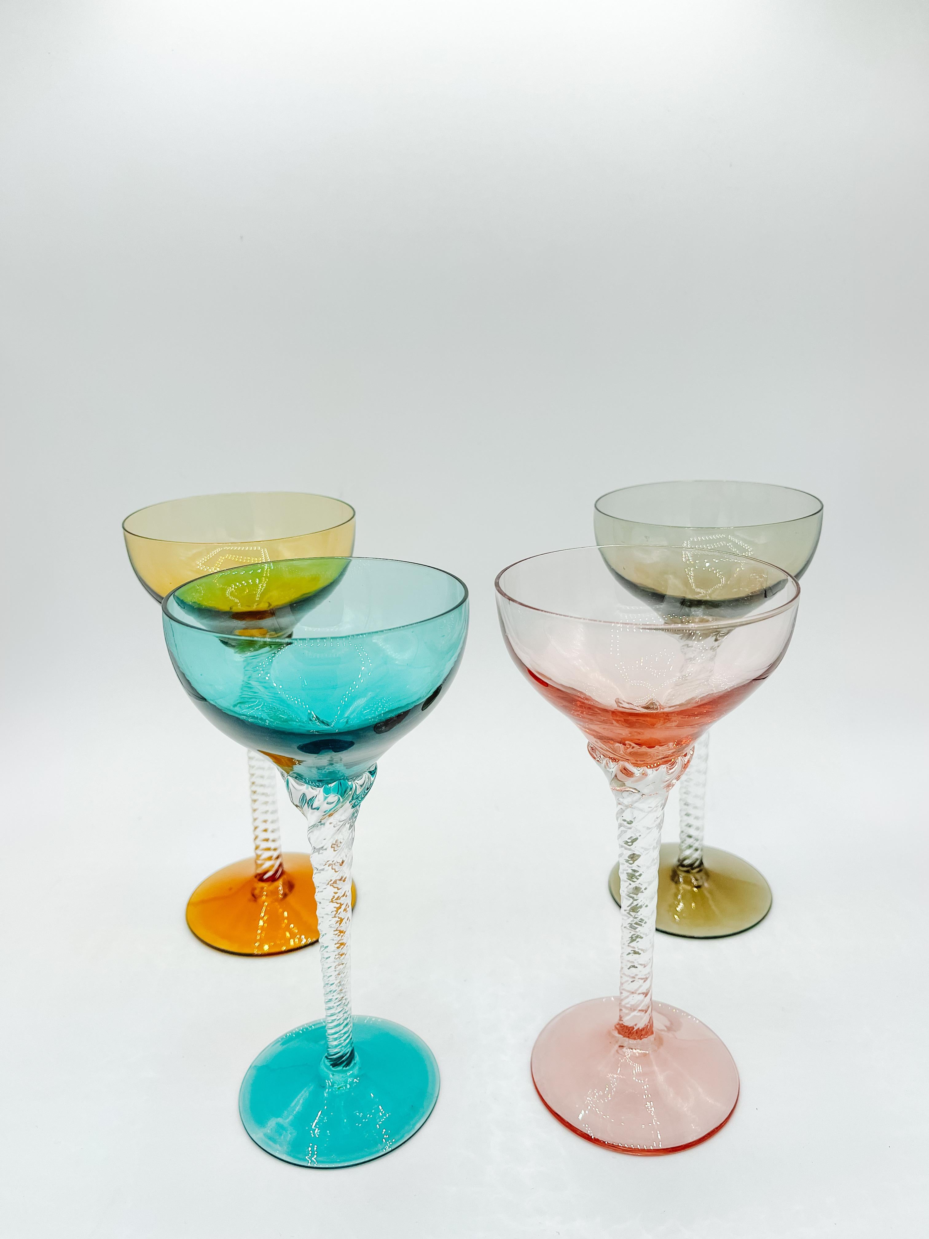 Dating back to the mid-20th century, these stunning martini glasses showcase the iconic Bohemian style of the 1960s. This set of four features vibrant, multicolored bowls in amber, blue, green, and smoky gray, beautifully complemented by intricately