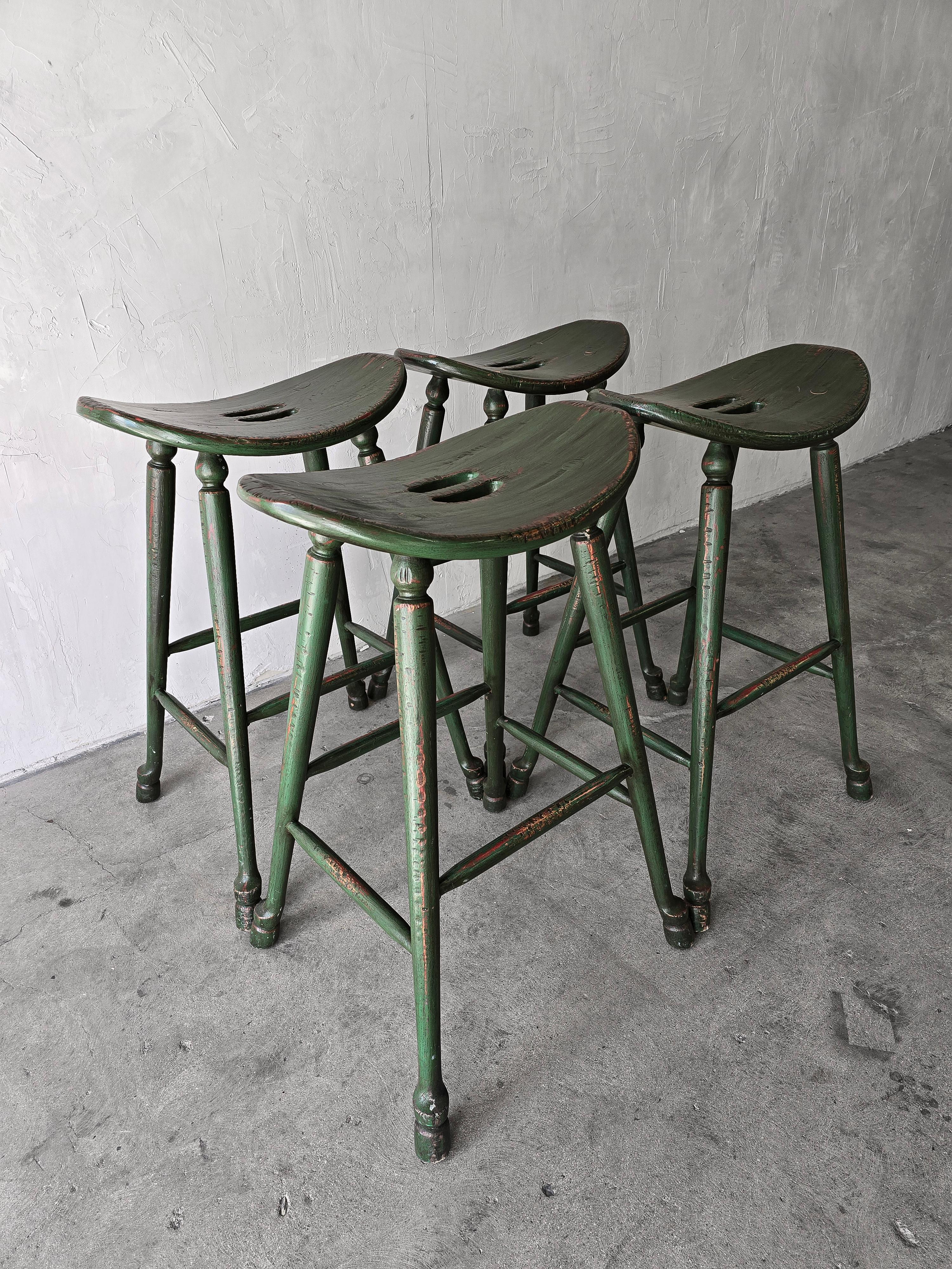 Superbe ensemble de 4 tabourets de bar vintage en chêne de style artisanal avec une finition d'origine vert foncé avec des détails en détresse qui leur donnent un air de campagne française.  Belle construction en goujons et grands sièges de selle.