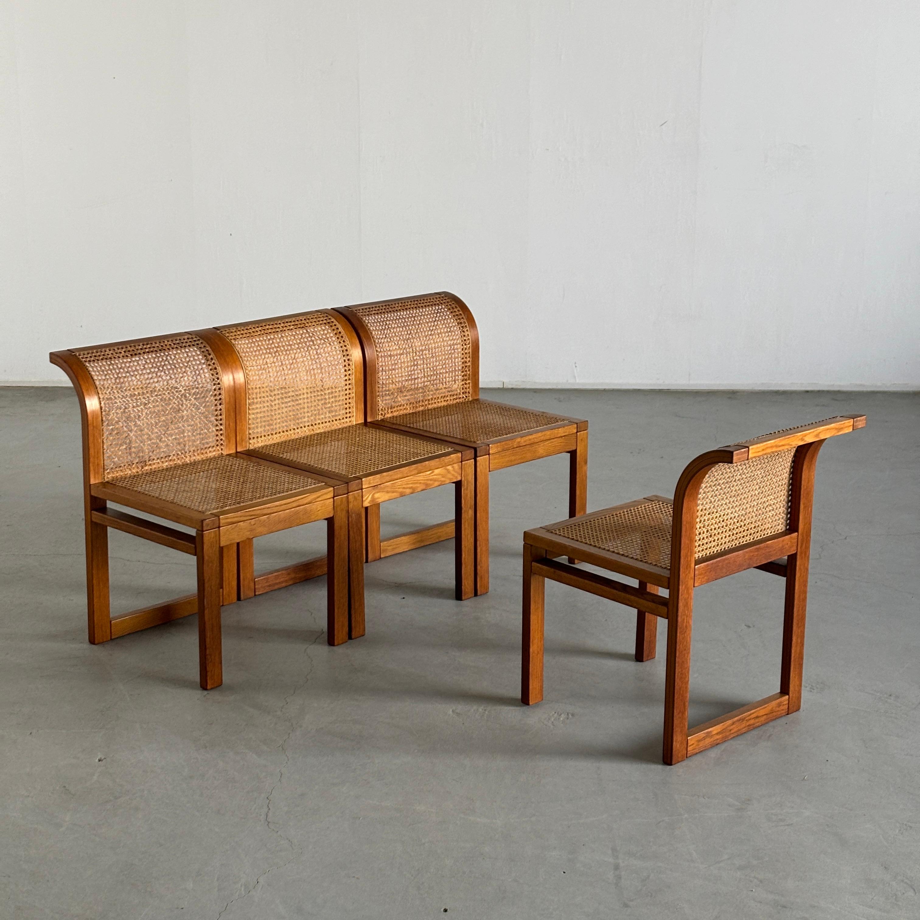 Set of four elegant dining chairs by Italian designer Luigi Massoni for Fratelli Boffi. Comprised of a wooden frame which curves backwards at the top with rattan seats and backrests. Subdued and minimal mid-century design. The chairs function