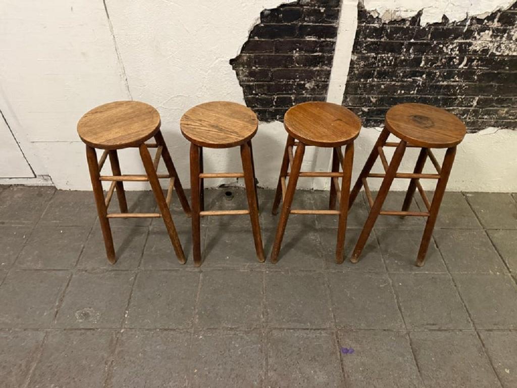 Set of 4 vintage French arts and crafts solid oak wood stools. Great matching set of four stools. They are all standard bar height at 30” high and 13” round seat. Hand made circa 1940 France. Located in Brooklyn NYC. Lots of patina fading wear use,