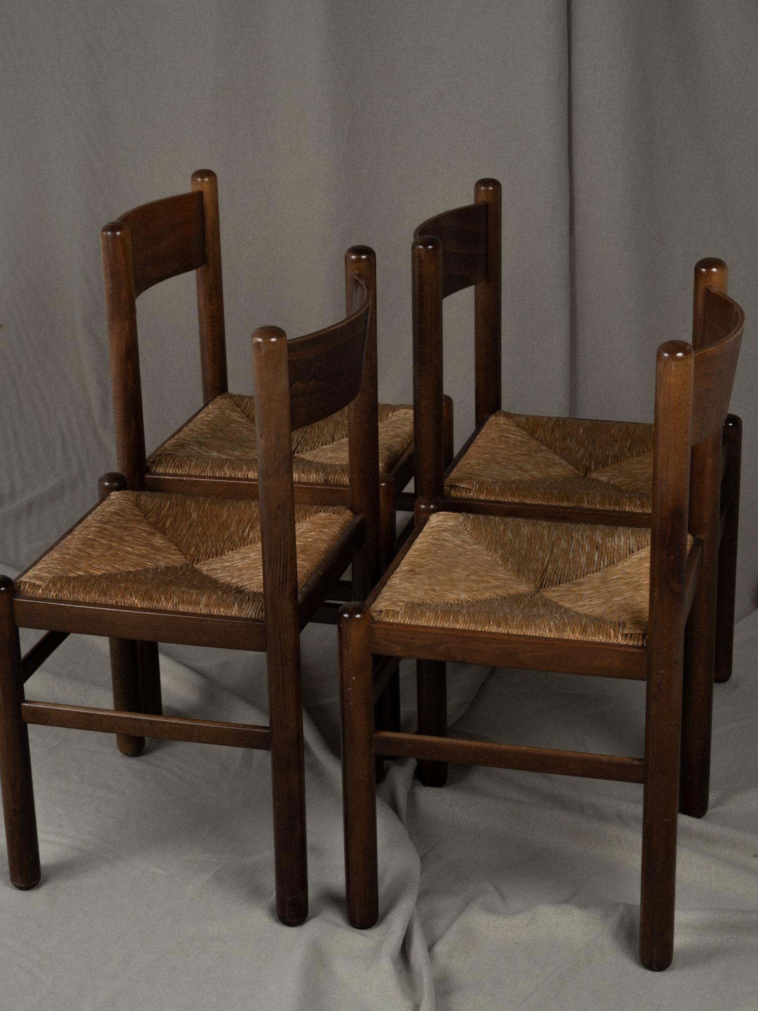 Beautiful set of 4 vintage dining chairs in the manner of Charlotte Perriand, circa 1970s. The chairs feature an open back with a horizontal slat design, showcasing a simple yet elegant style with a touch of modern aesthetics. Solid, dark brown