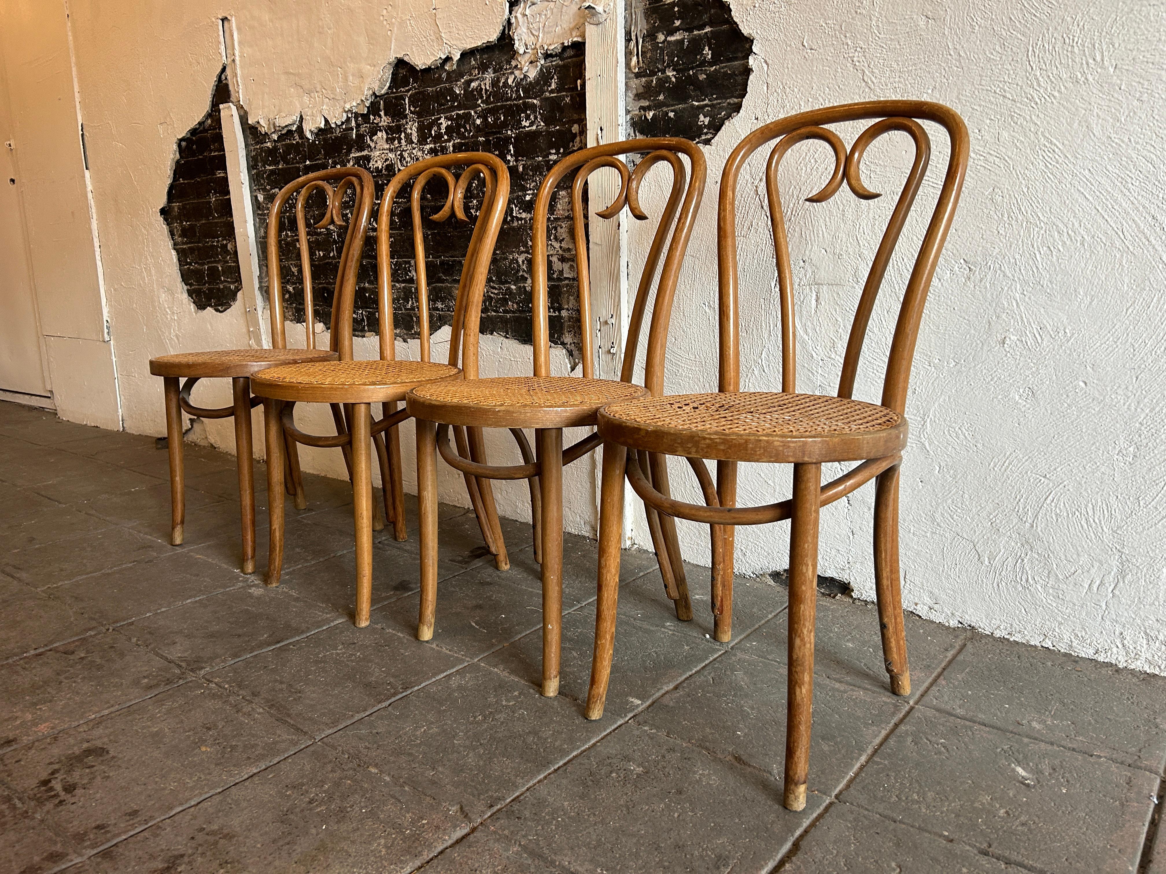 Set of 4 Mid century vintage cane seat cafe chairs by Thonet. Sweetheart chairs. They are in original condition with nice patina. The light Brown Walnut wood has been oiled showing honest wear and ready for use. All Cane is in hand done and original