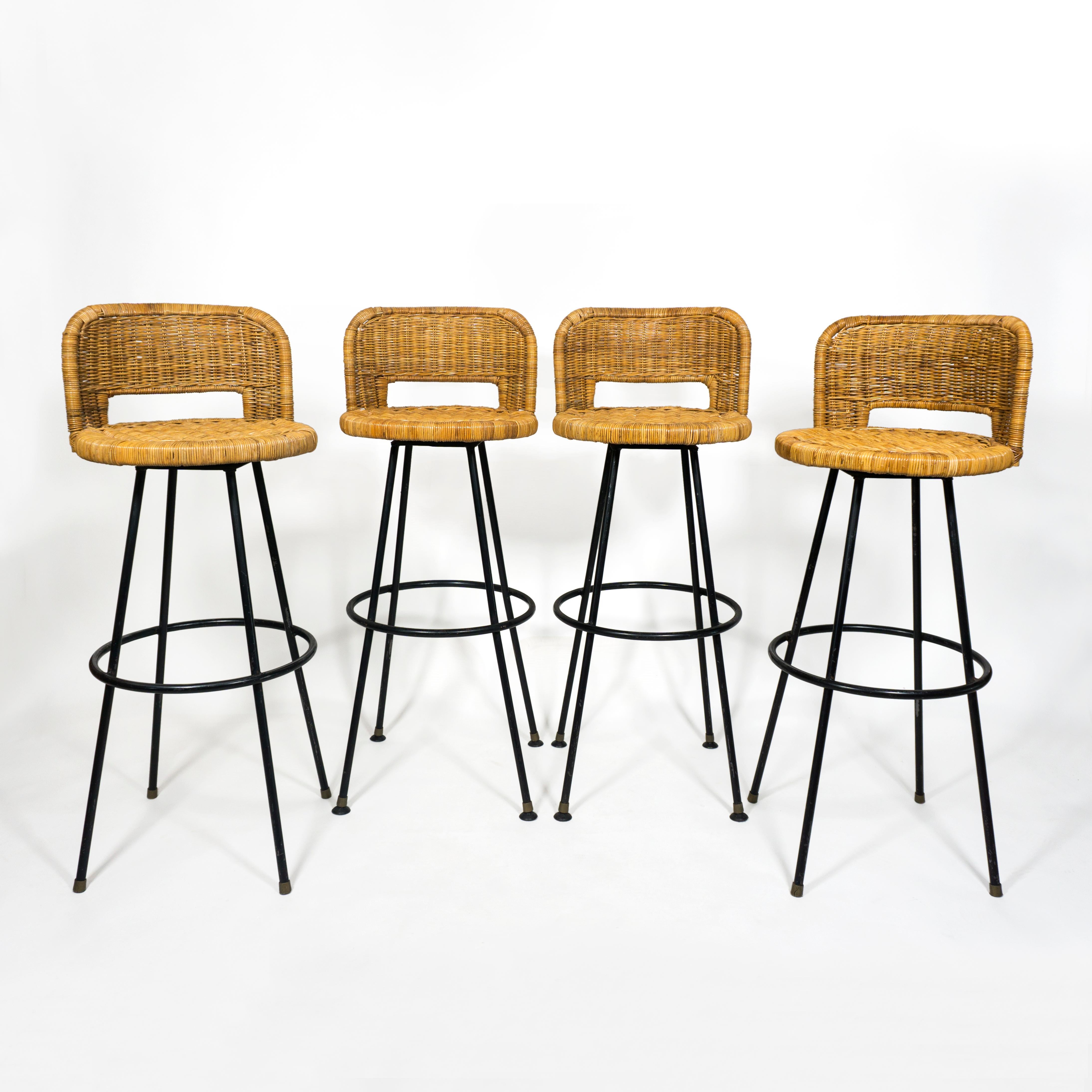 Set of 4 vintage swivel bar stools with wrought iron base and wicker and bamboo seat in the style of Danny Ho Fong
Thanks to the rounded backrest and the footrest, the chairs are extremely comfortable and sturdy and all stools swivel smoothly. 
Two