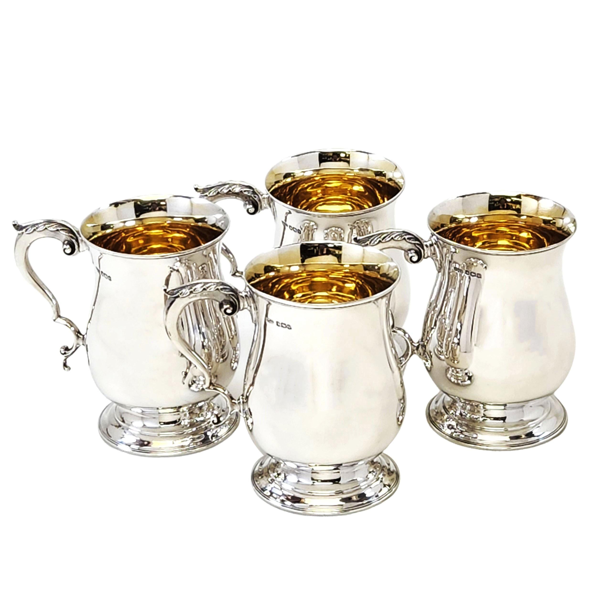 A set of Four Sterling Silver 1/2 Pint Mugs in a traditional Georgian Style, with a polished baluster shaped body, standing on a spread foot and featuring a scroll handle topped with an acanthus leaf. The interior of each Tankard is gilded. The