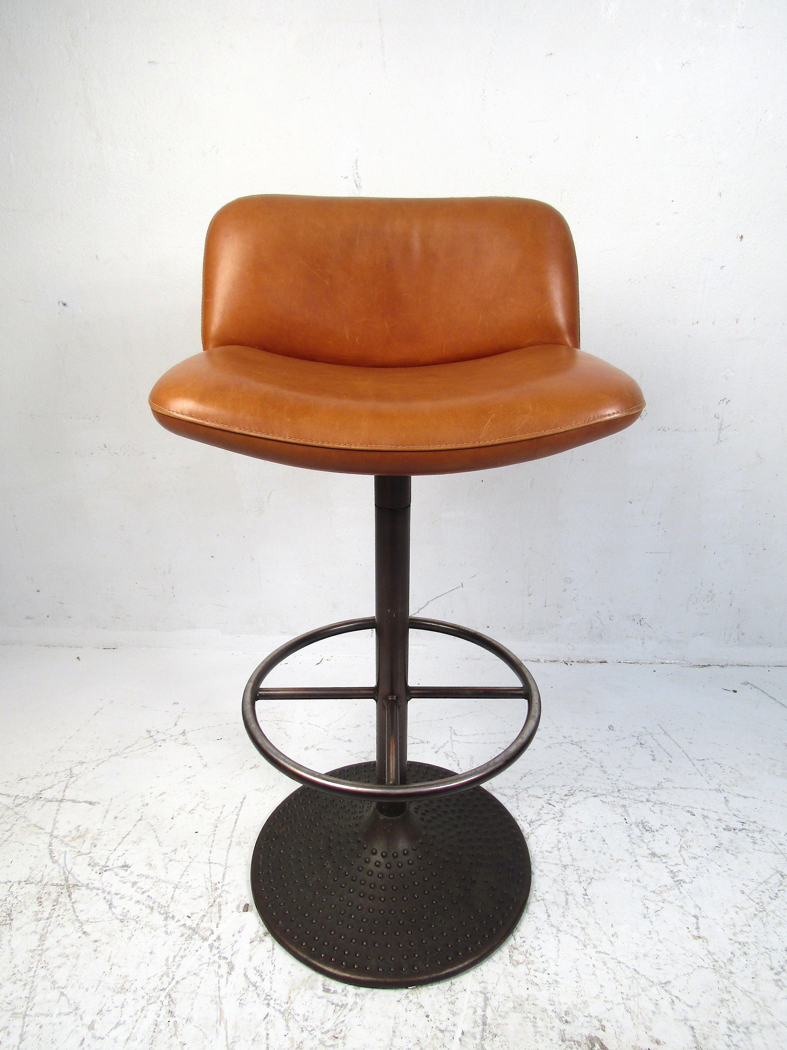 Stylish set of four upholstered swiveling bar stools. Sturdy metal base and stem with an interesting studded pattern adorning the base of the stools. Covered in a vintage orange faux-leather upholstery. Nice set sure to complement any modern