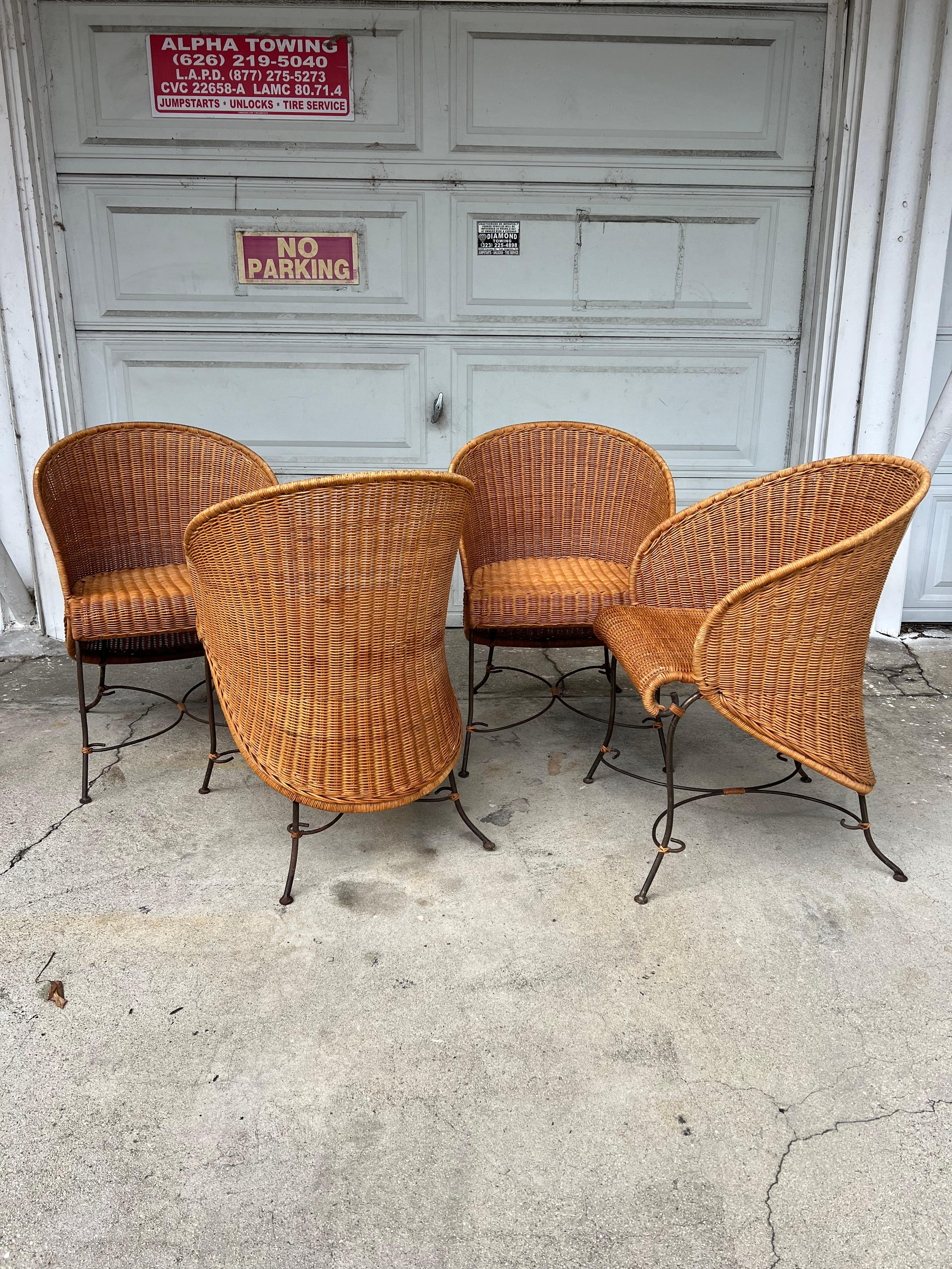 Set of four rare wicker and wrought iron dining or patio chairs. The curves on these- magnificent from every angle. A cinched waste silhouette from behind. Sturdy wrought iron frames with small wicker tie details at base. Woven wicker backs and