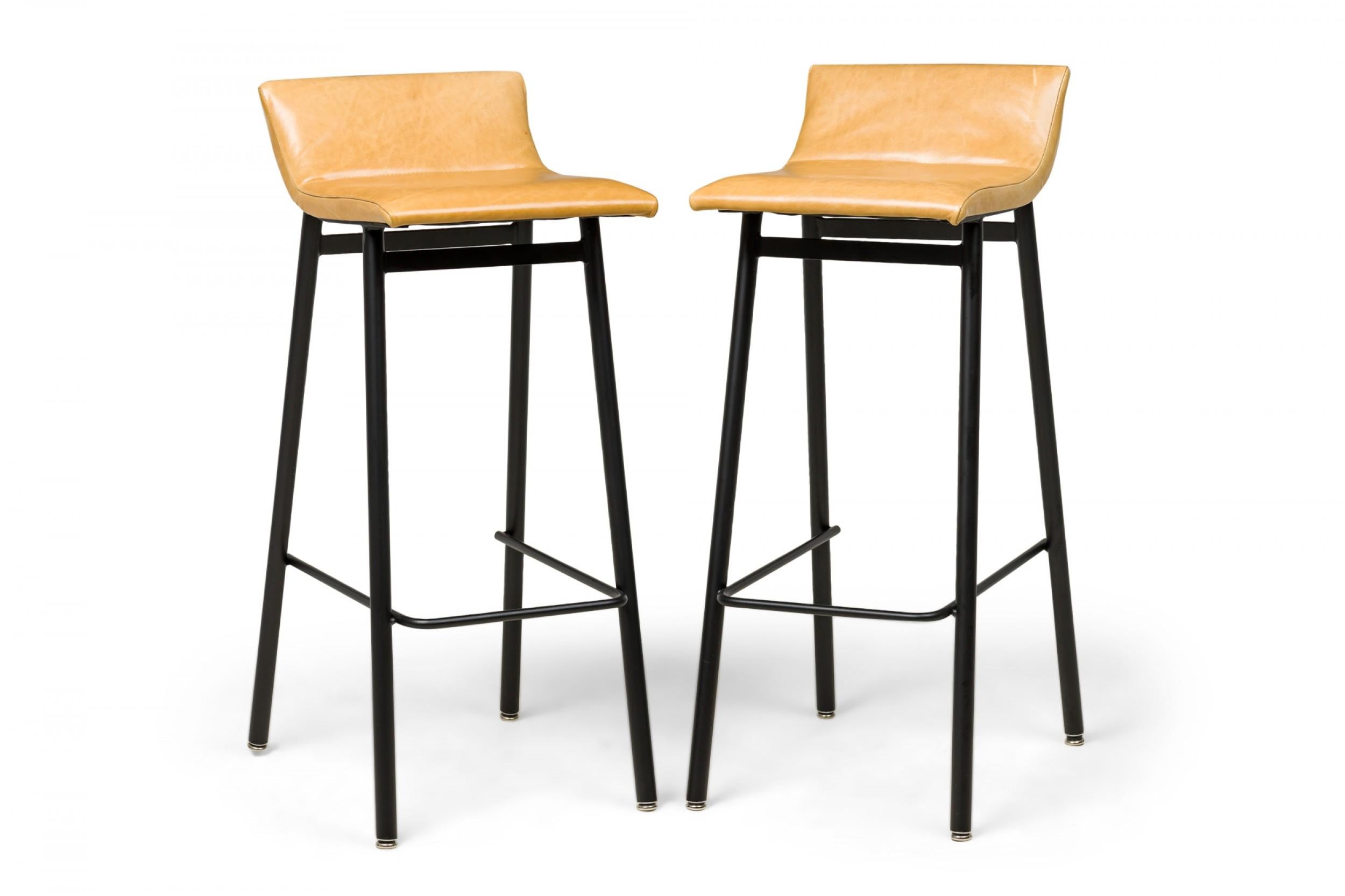 Ensemble de 4 tabourets de bar américains du milieu du siècle en émail noir avec des sièges en vinyle rembourrés à la moutarde et des dossiers légèrement inclinés soutenus par un cadre d'assise en forme de U, reposant sur 4 pieds évasés. (VISTA)