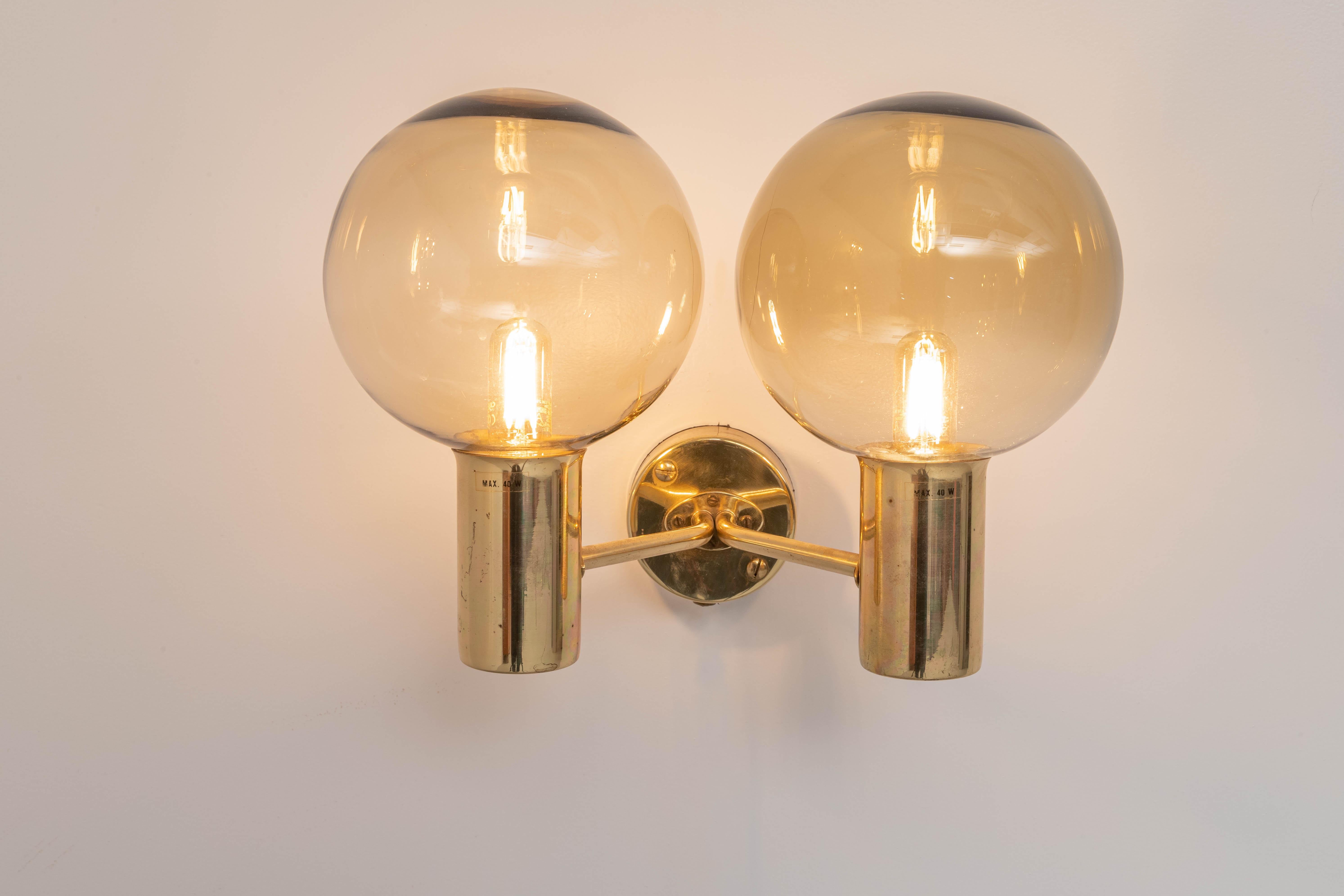 Wall light of the famous V 149/2 series with double executed light points in brass and light-brown smoked glass by Hans-Agne Jakobsson, 'The master of dimmed light'. 

The further up north you go, the longer and darker the winters, so the