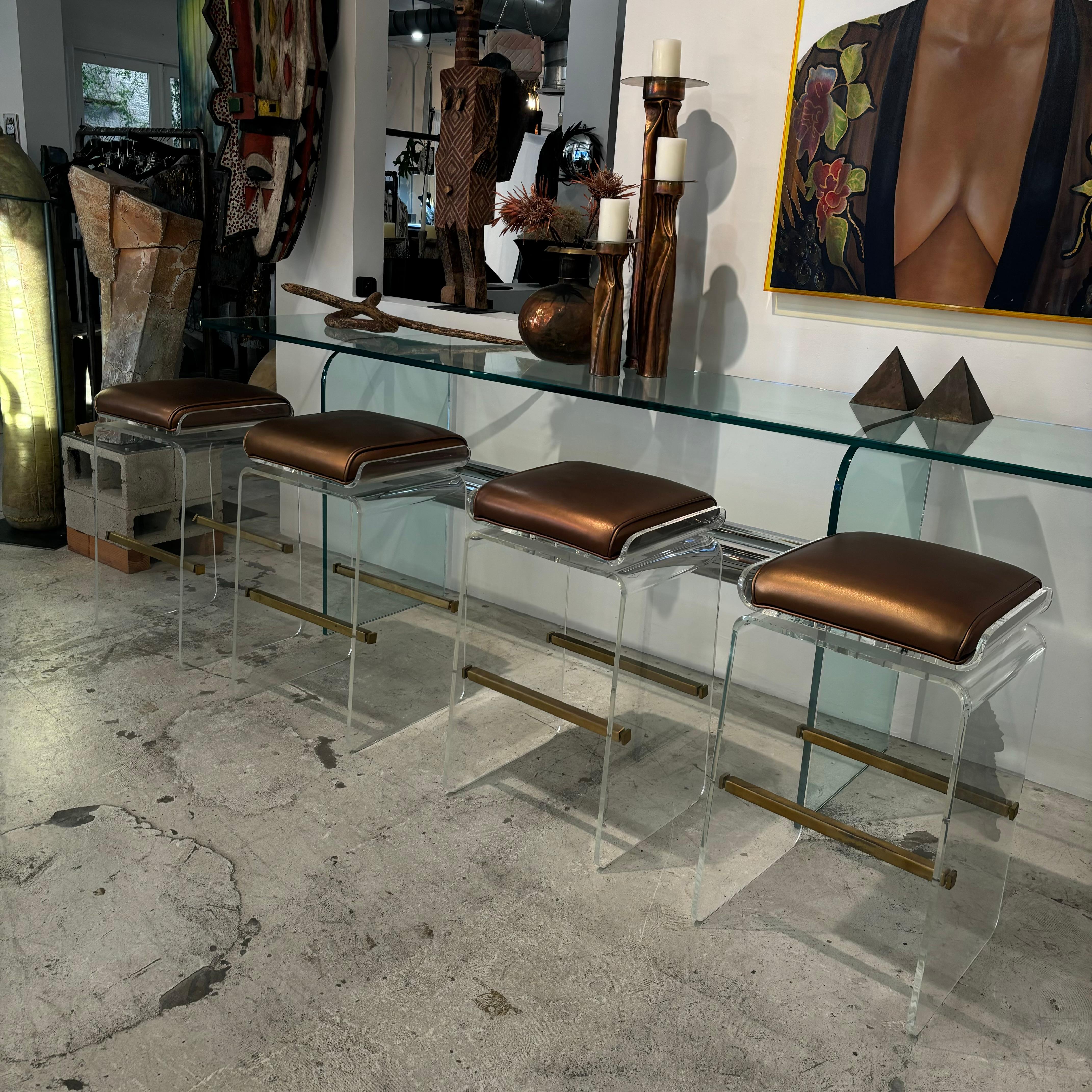 Set aus 4 drehbaren Barhockern aus Lucite und Messing mit kupferfarbener Lederpolsterung 

Entworfen von Charles Hollis Jones

1970s

In gutem Vintage-Zustand mit alters- und gebrauchsbedingten Gebrauchsspuren.

