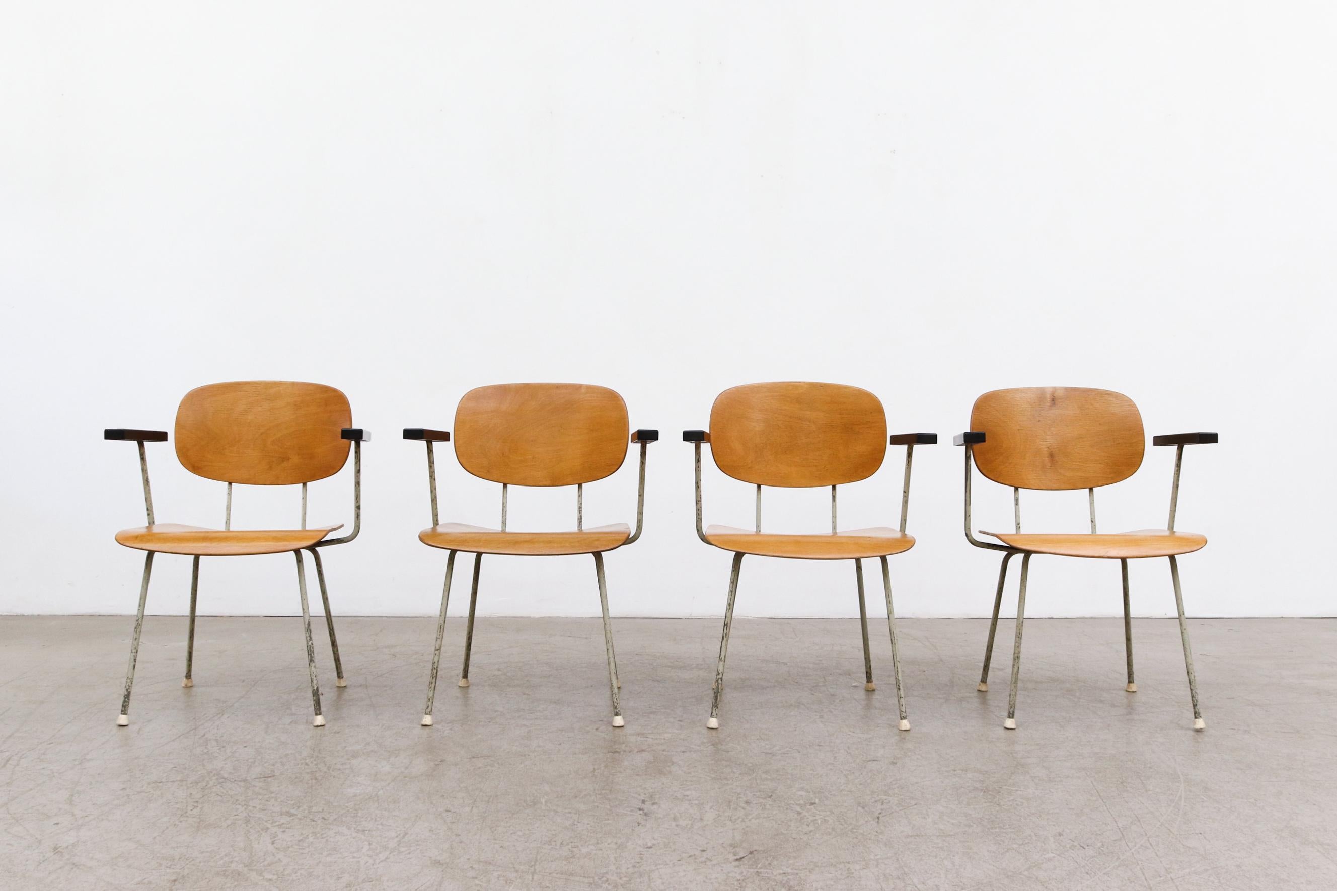 Mid Century Dutch great Wim Rietveld's Model 216 arm chairs with lightly refinished beech plywood seating and black bakelite armrests. Original frames with some visible wear and patina. New rubber mounts glued on bottoms, as a replacement for the