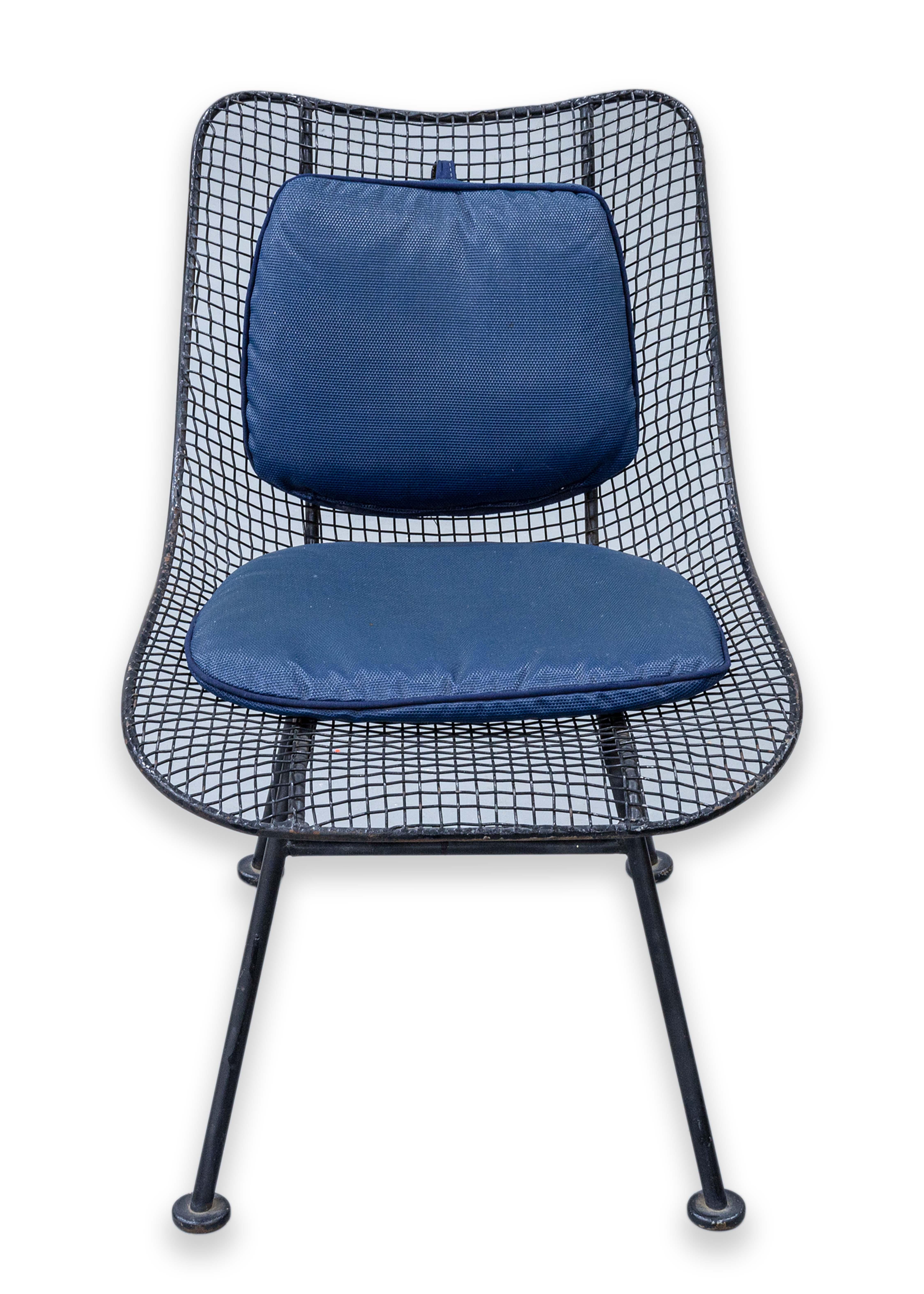 A set of 4 wrought iron Woodard patio chairs. A beautiful set of patio chairs with a classic mid century styling. These chairs feature a black wrought iron construction, with a wire frame design. These chairs have removable blue seat rests and back
