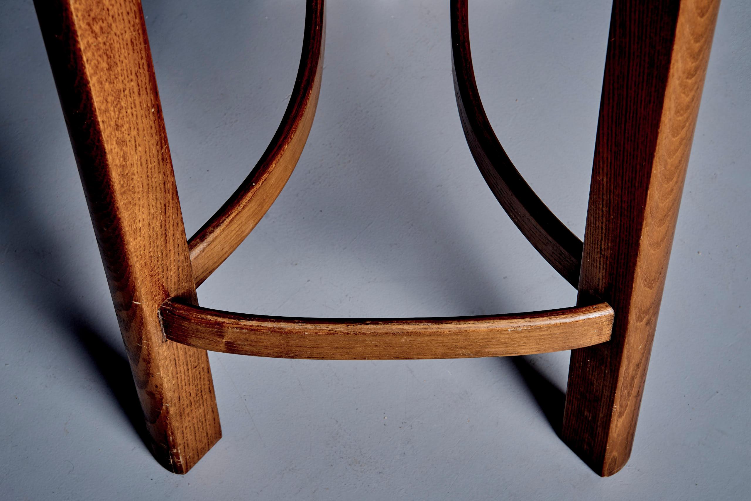Ensemble de quatre hauts tabourets de bar italiens des années 1970, en frêne massif teinté noyer avec assise en rotin tressé. Le design se caractérise par des dossiers hauts et divisés avec des sommets arrondis, des lignes géométriques épurées et