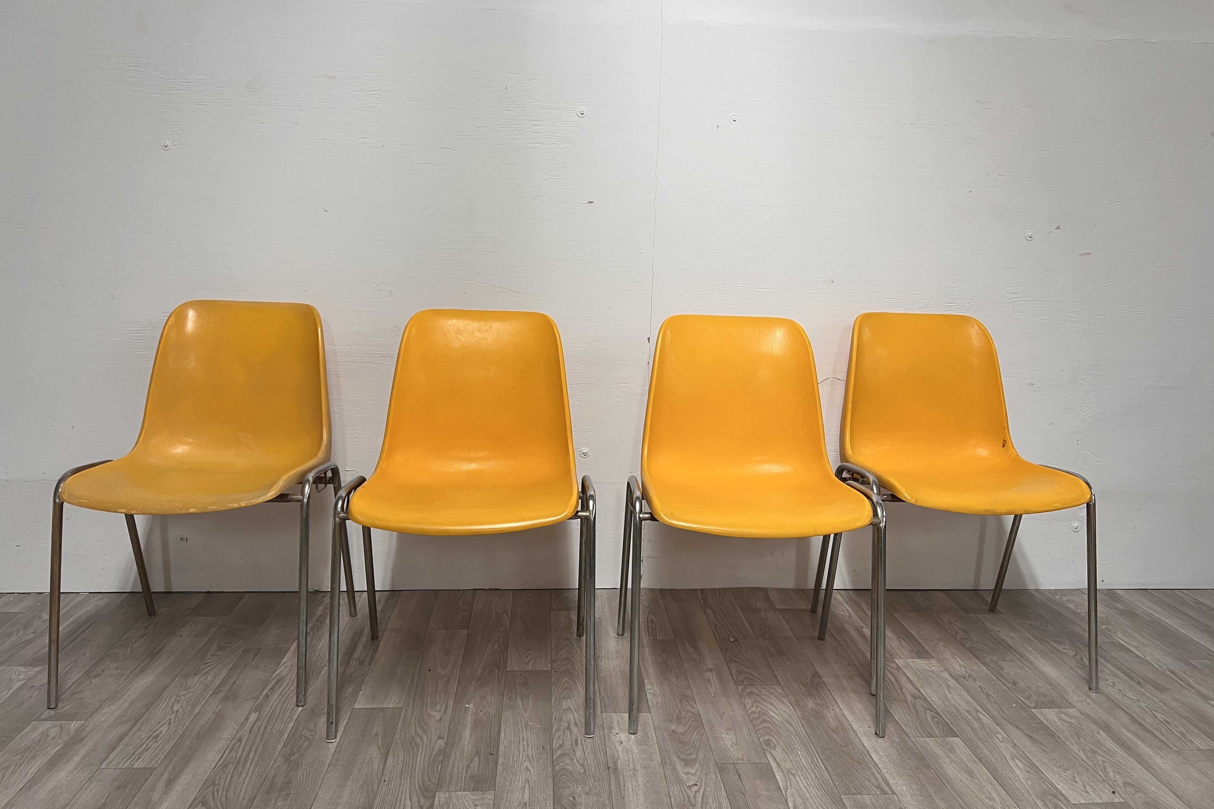 Ensemble de quatre chaises à coque en plastique jaune sur une base en métal chromé 
Condition Vintage