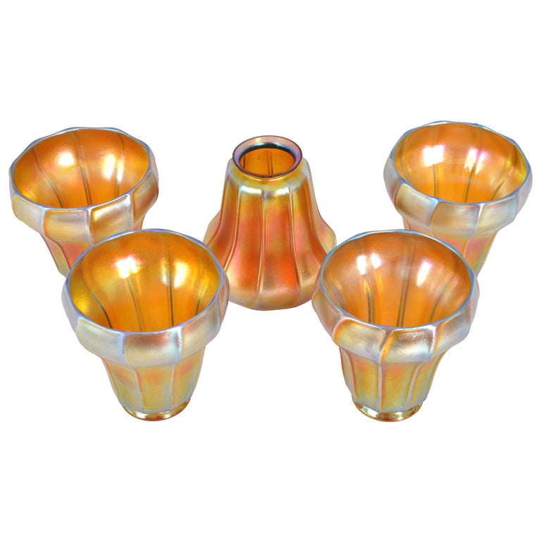 A set of five antique Steuben gold Aurene Arts Nouveau lampshades, circa 1910. The shades of bell-flower shape and having ribbed decoration, the shades are a warm iridescent gold color and each shade is signed with the Steuben fleur-de-lis mark.