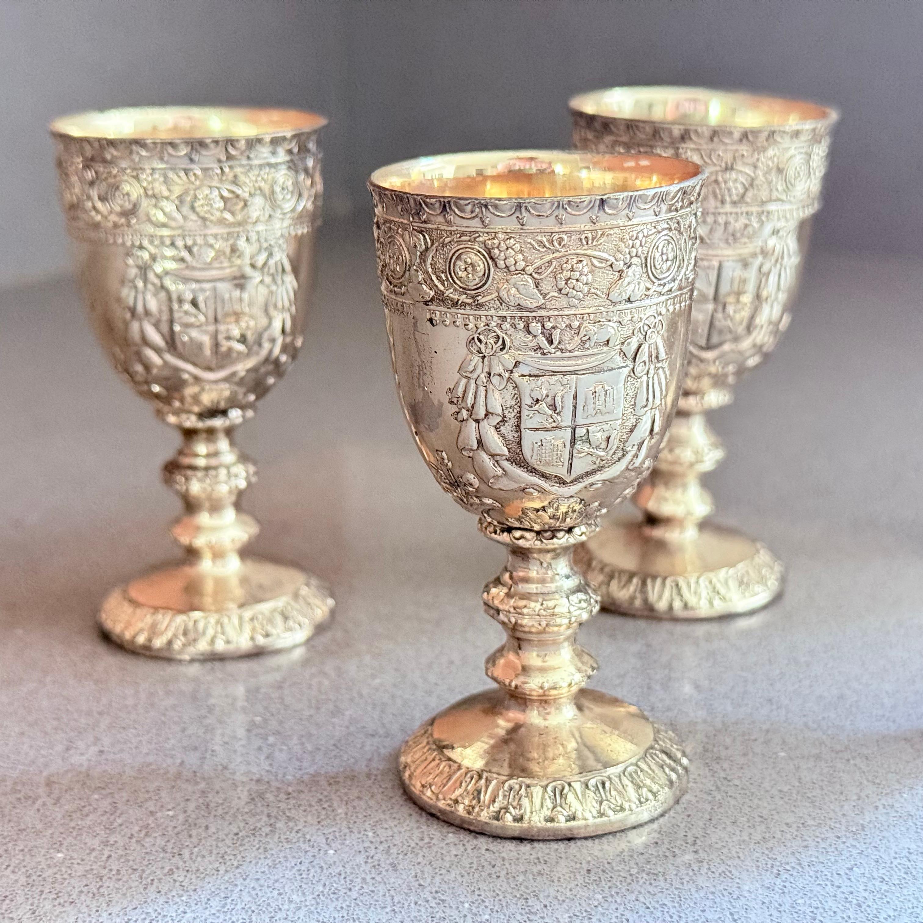 Un bel ensemble de cinq coquetiers en argent plaqué, chacun richement décoré dans un style antique revival avec des motifs floraux et héraldiques ornés en repoussé. Les intérieurs sont dorés (lavés à l'or), ce qui apporte à la fois élégance et