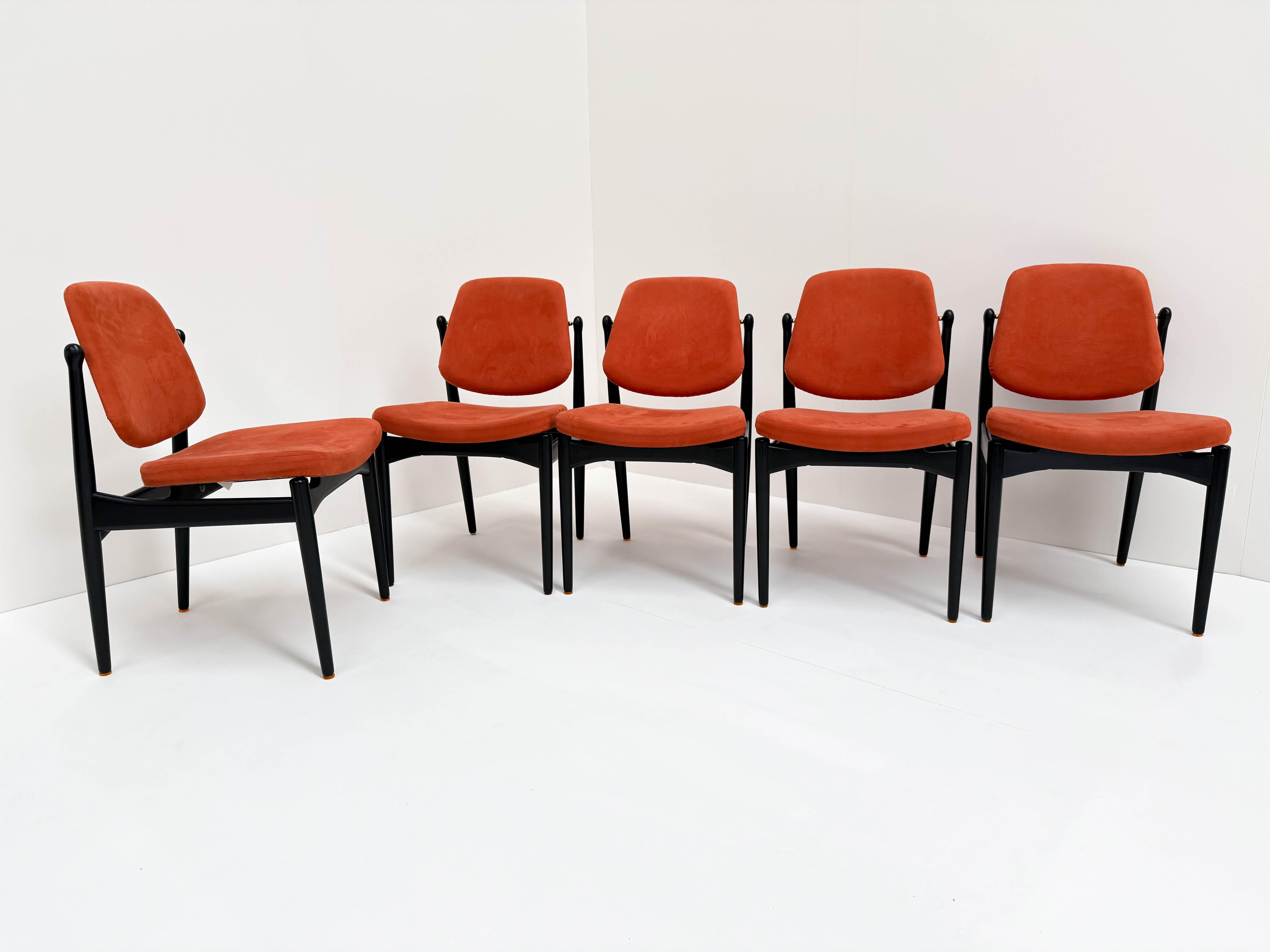 An exquisite set of five mid-century modern dining chairs designed by renowned Danish architect Arne Vodder and produced by France & Son. The sleek black wooden frames contrast beautifully with the burnt-orange upholstery, showcasing Vodder’s