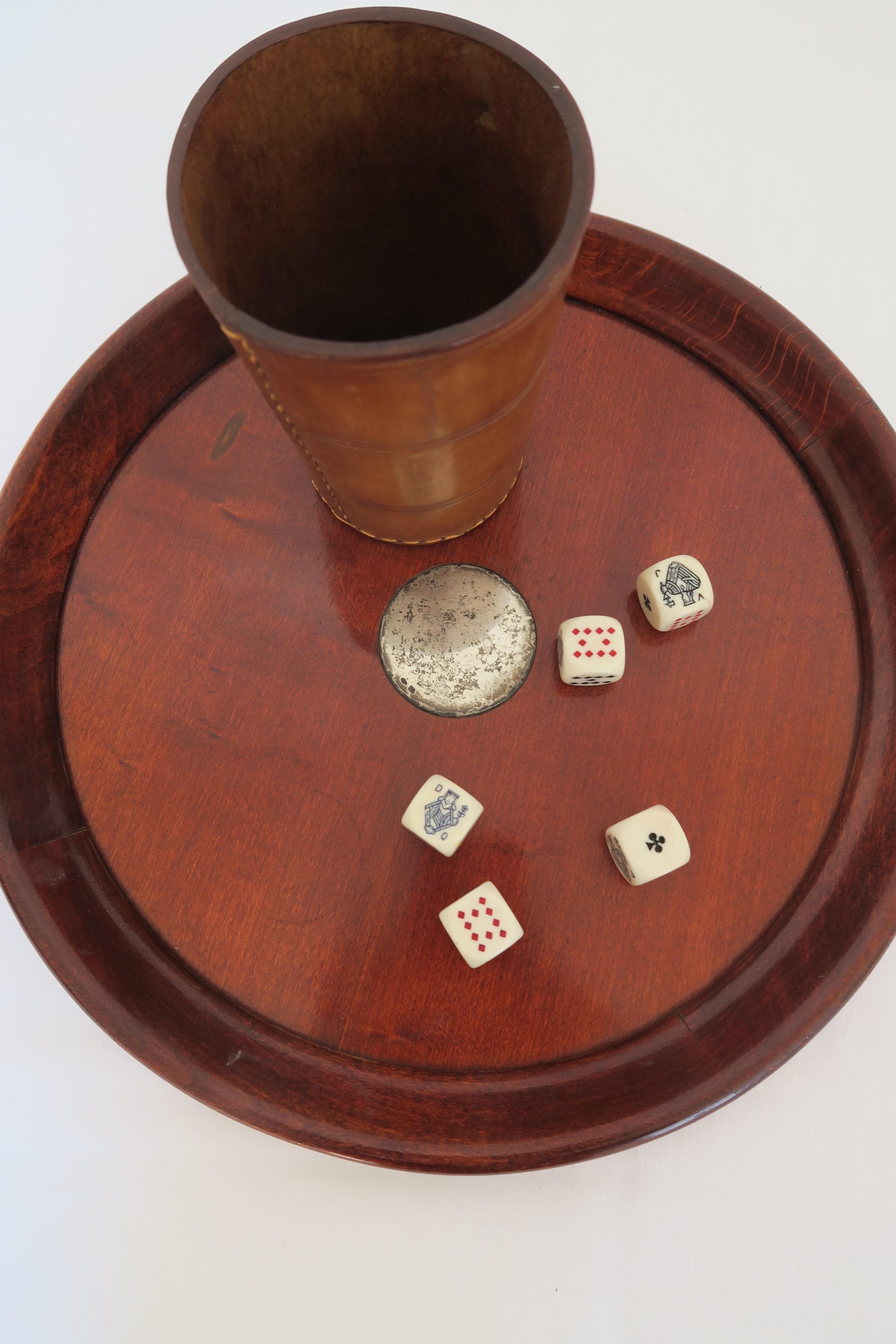 This is a set of 5 dice, a dice cup and wooden tray with silver inlay. The cup made from pigskin leather is exquisite to touch. On the bottom you can find the stamp of the trusted purveyor of leather goods to the Austrian court who crafted this cup