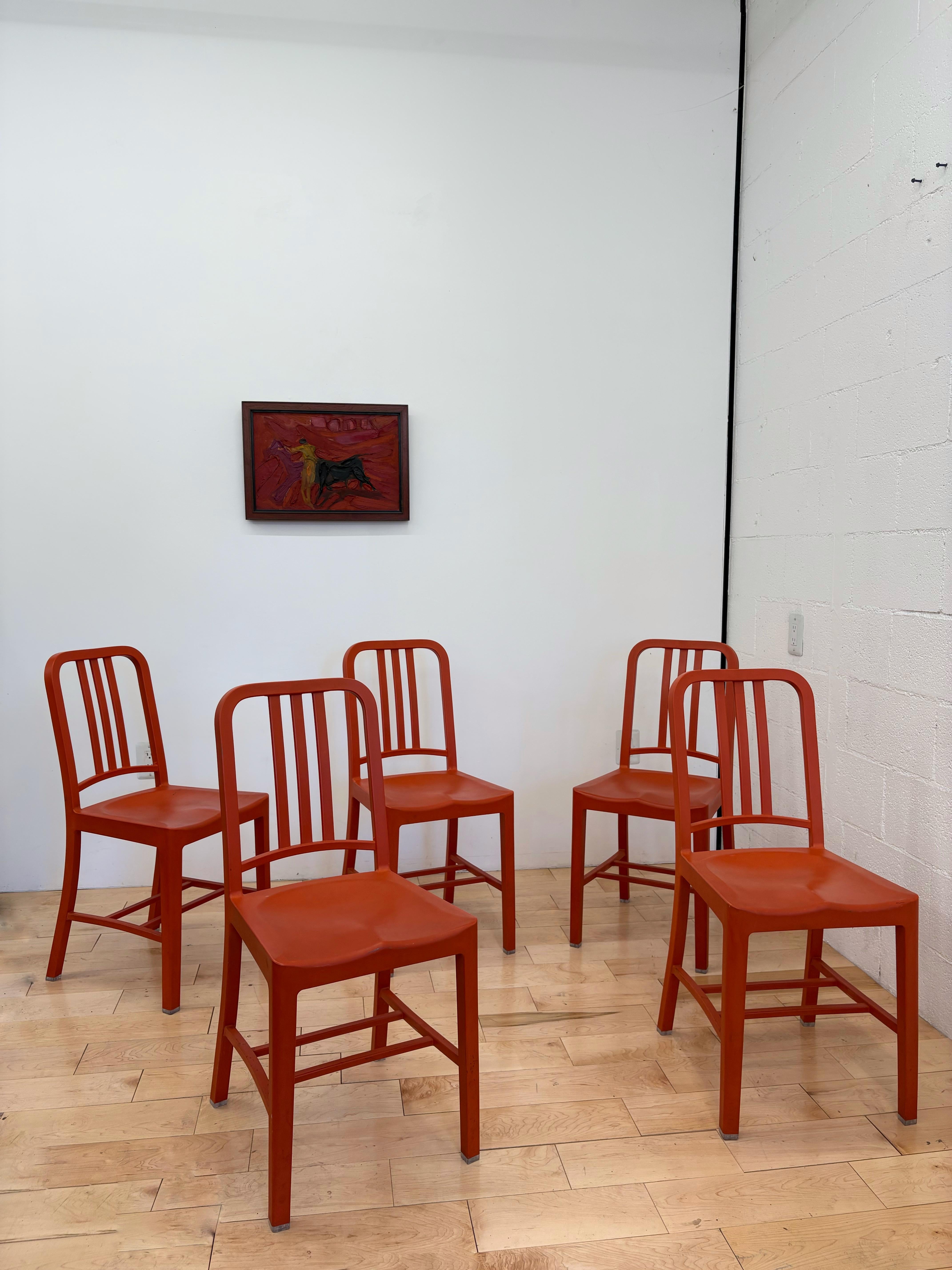 set of five Emeco 111 Navy Chairs in striking Coca-Cola red. Each chair is crafted from 111 recycled plastic bottles, a sustainable reinterpretation of Emeco’s iconic aluminum Navy Chair originally designed for the U.S. Navy in the 1940s. Durable,