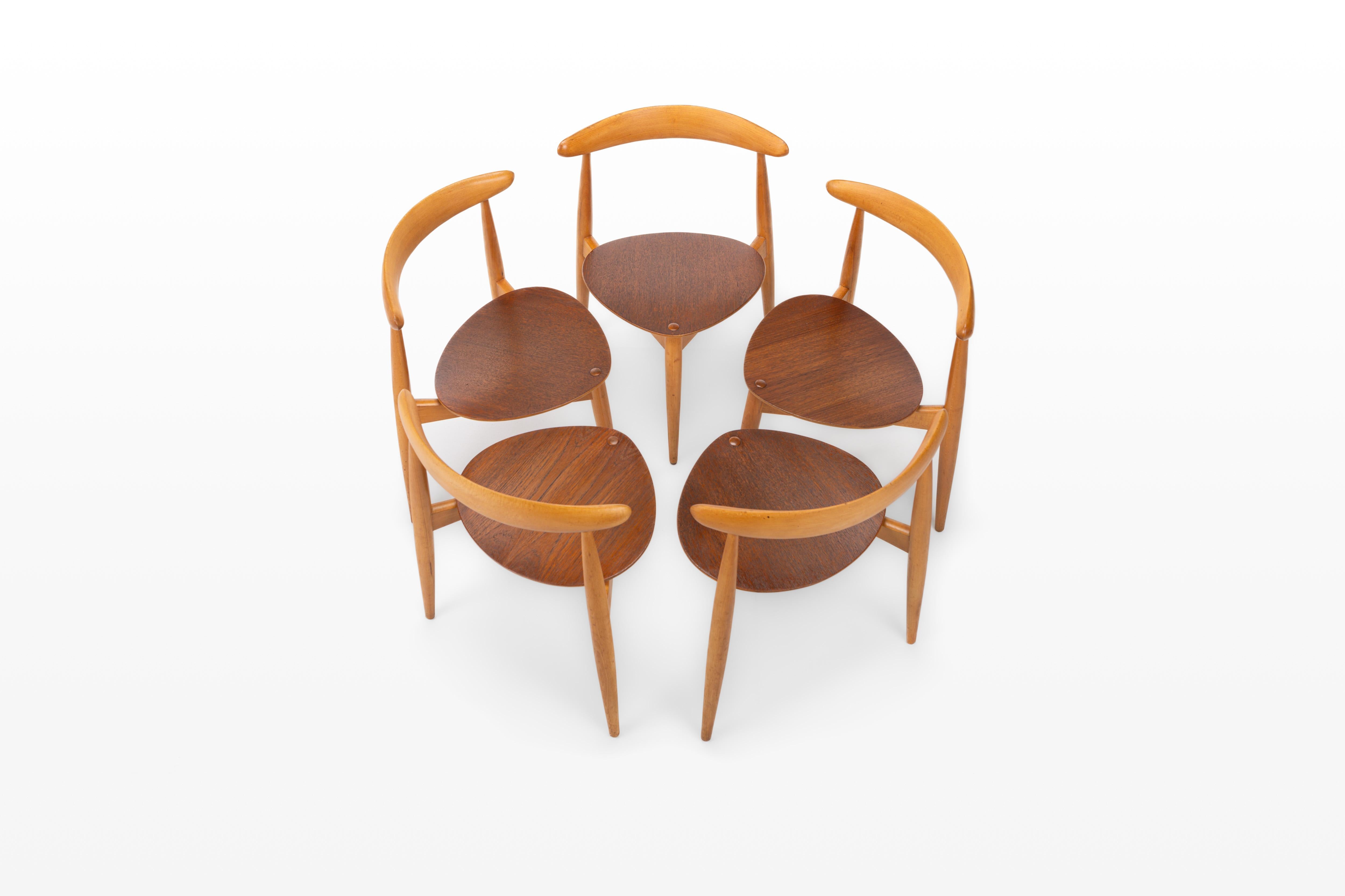 Set of five vintage 'heart' dining chairs designed by Hans J. Wegner for Fritz Hansen, Denmark 1950s. Designed as model 'FH4103'. The chairs have a beech frame and a teak seating. These three-legged chairs are stackable and are in great