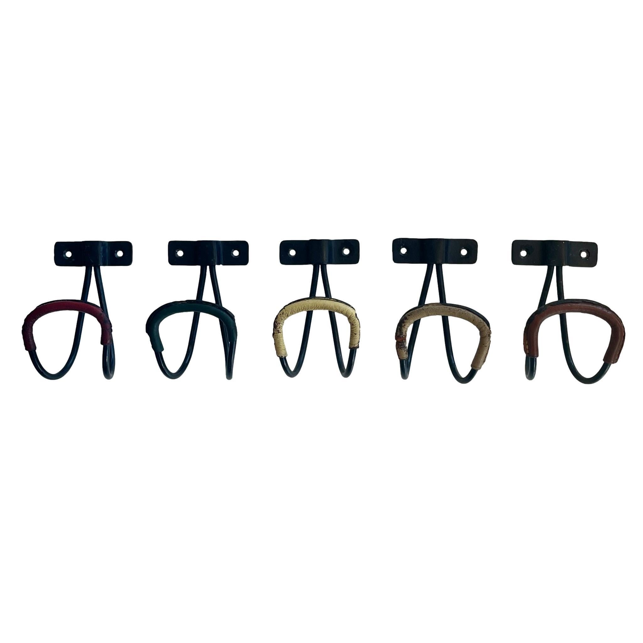 Amazing collection of wall hooks by French designer Jacques Adnet. Perfect for hats or coats. Iron frame with leather wrapped hooks. Saddle brown, off-white, yellow, red and green colors. All finished with signature Adnet contrast stitching. Sold as