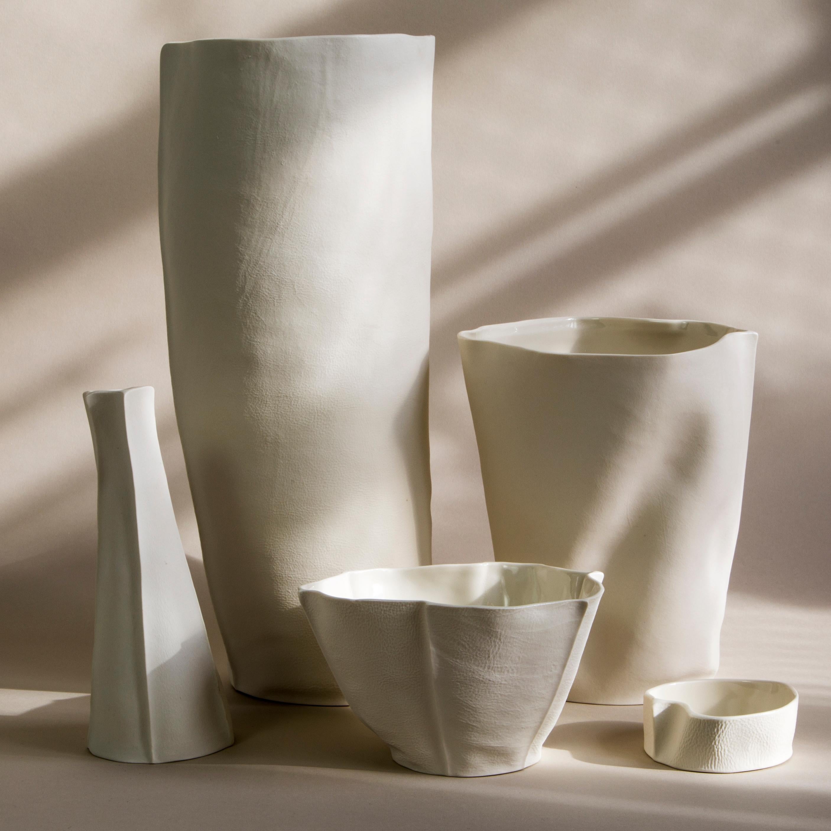 A set of 5 leather-cast porcelain vases & bowls with textured exterior surface and clear glazed interior. Dynamic and organic in form, the set can be used as a cluster or individually. Perfect for styling a foyer console, modern credenza, or as a