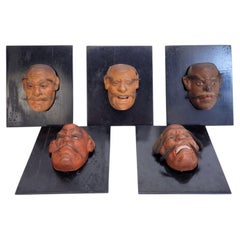 Ensemble de 5 masques de théâtre nô japonais Meiji, montés sur bois ébonisé.