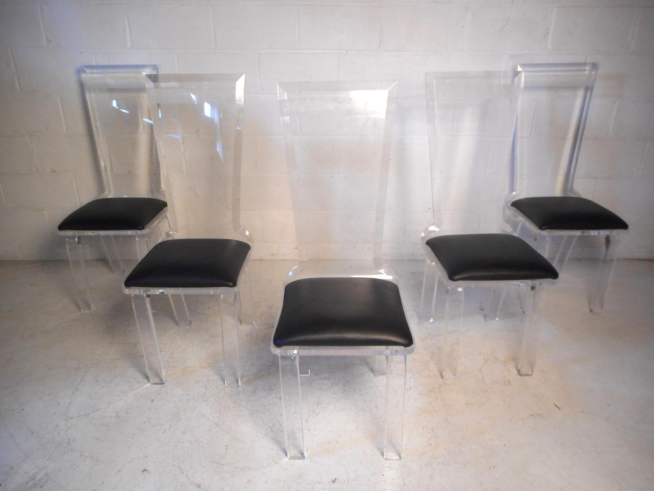 Questo esclusivo set di sedie da pranzo di metà secolo presenta una struttura in lucite scolpita, alti schienali svasati con interessanti dettagli strutturati ed eleganti rivestimenti in ecopelle. Un'ottima aggiunta a un interno moderno. Lo stile è