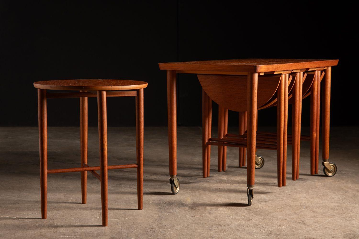 Set of four round folding snack tables that ingeniously nest beneath a fifth rectangular side table on casters. Designed by Carlo Jenson and produced by Hundevad Of Denmark. A very functional design.