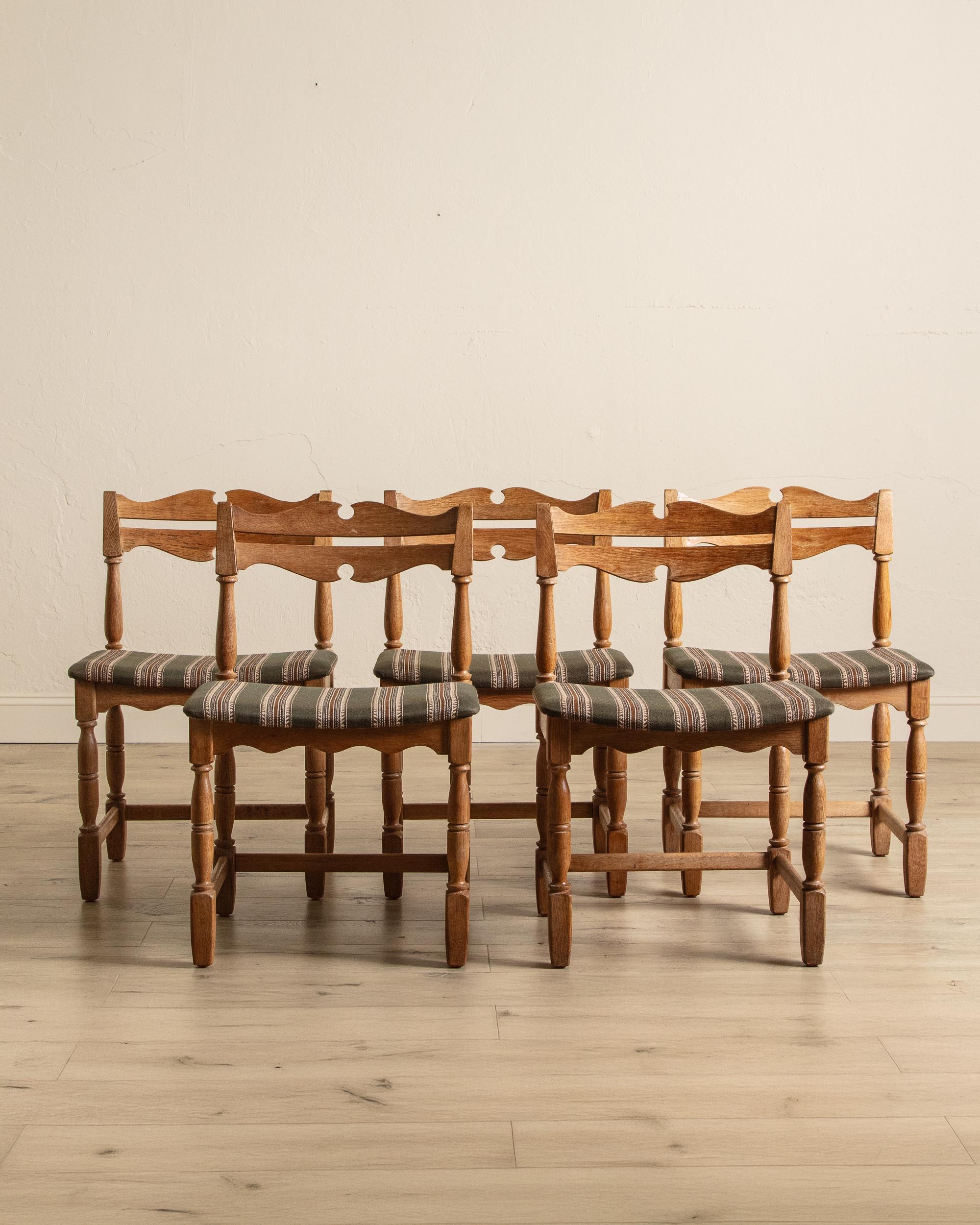 This set of five French Provincial dining chairs offers a warm blend of rustic craftsmanship and classic design. Each chair features a carved ladder-back with gentle curves and subtle cut-out detailing, lending character to the simple silhouette.