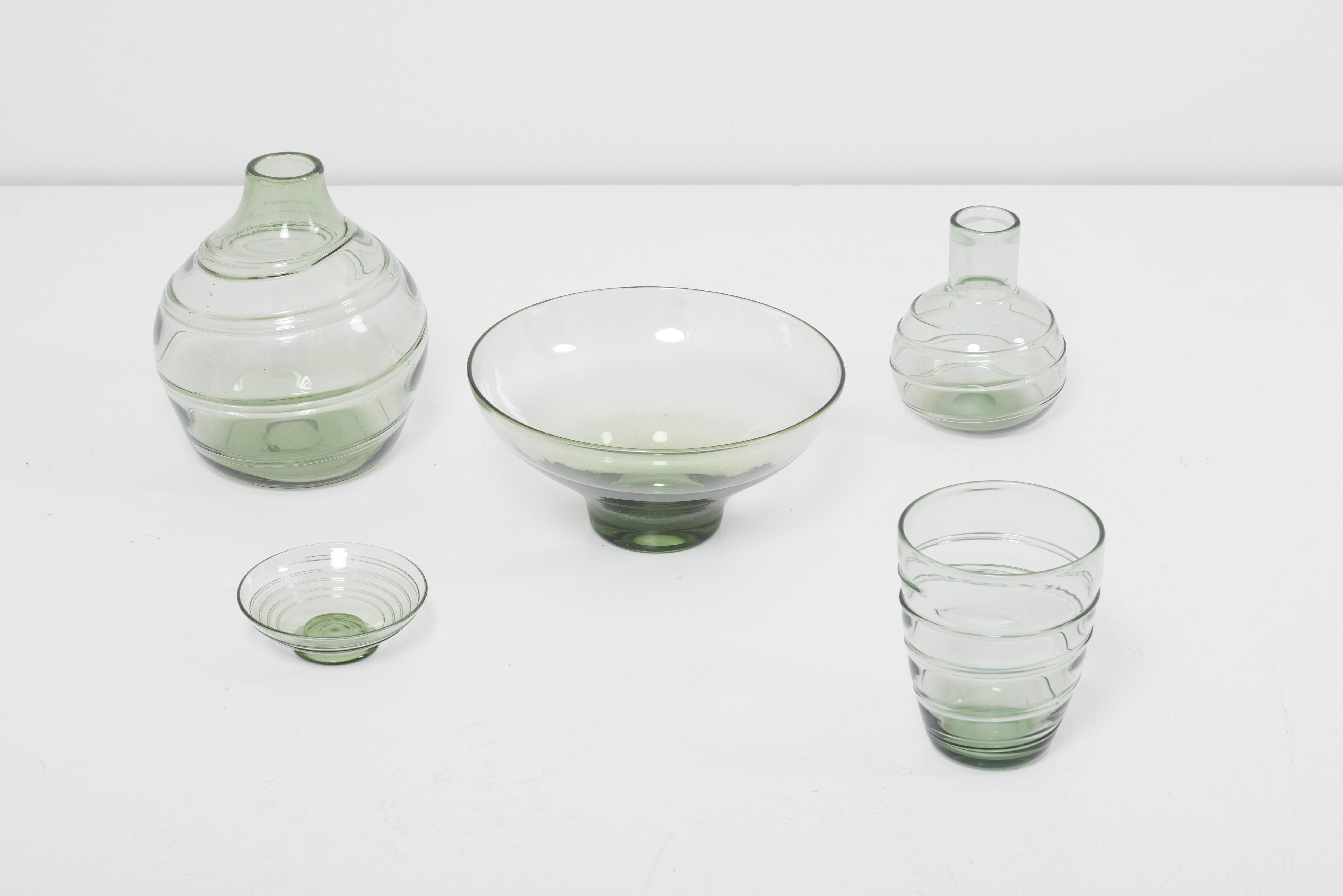 Collection of ribbon-trailed glass vases and bowls in green.
Designed 1930s by Barnaby Powell for Whitefriars, UK.
The dimensions given apply to the largest vase.