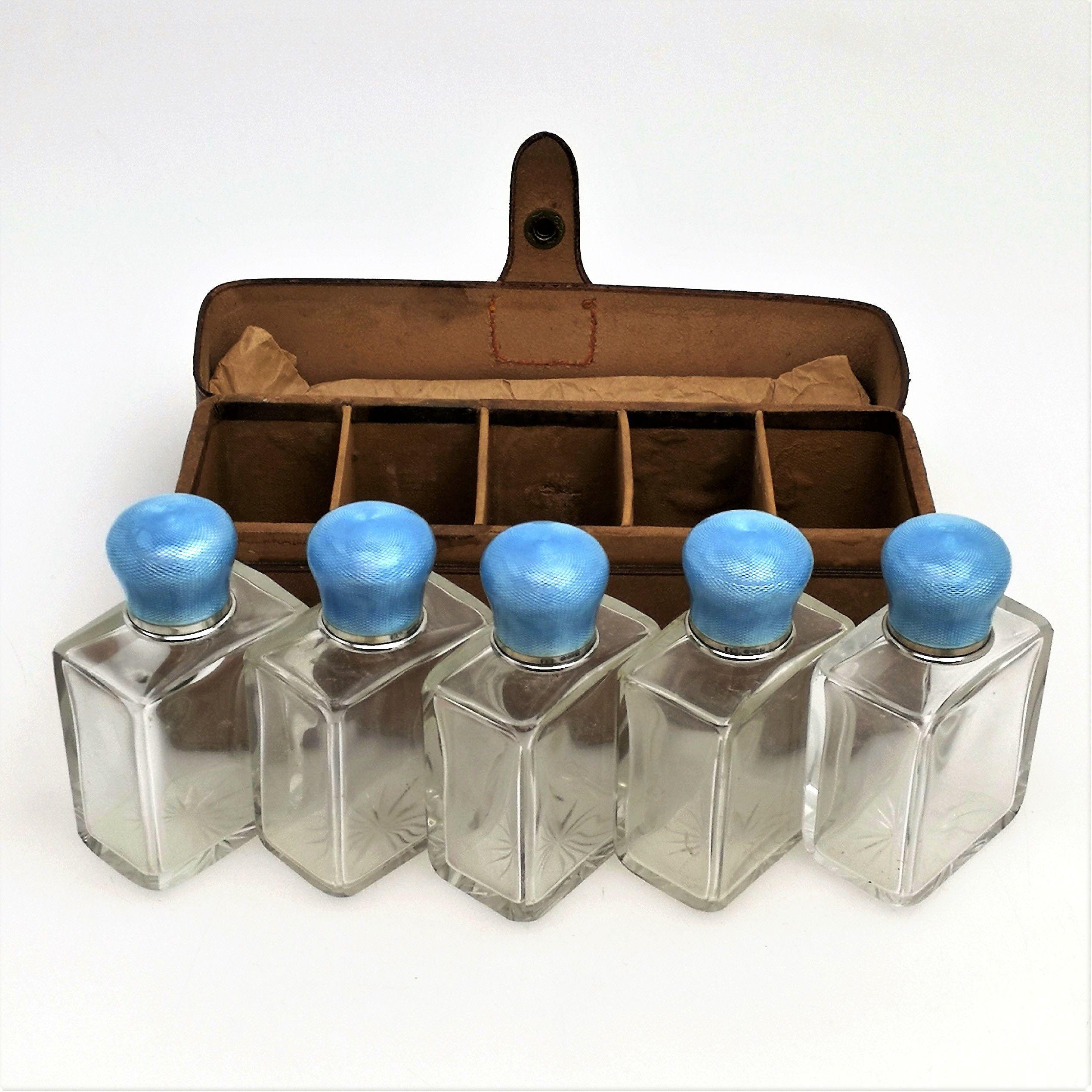 A set of 5 matching Sterling Silver and Guilloche Enamel lidded glass Bottles in a fitted leather travel case. The push fit Lids are a gorgeous rich blue enamel and the bottles are clear glass rectangular bottles with a simple star cut pattern on