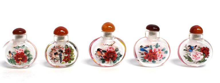 Our snuff bottles are 100% hand painted from within and topped with gemstone agate lids. The Chinese art of églomisé uses a very thin bamboo brush with a few strands of hair to apply watercolor on the inside walls of the blank glass bottle