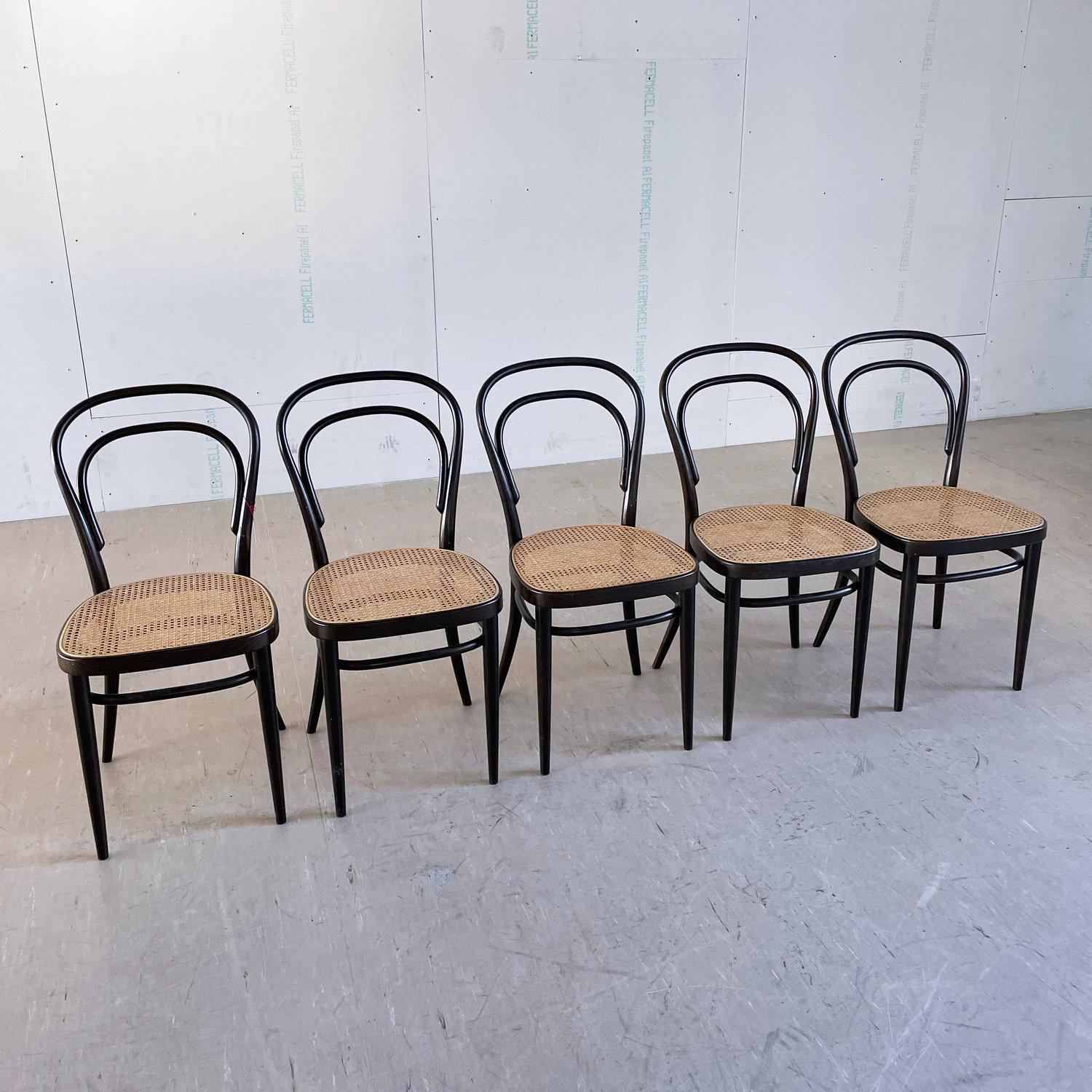 Satz von 5 Thonet #214 Vienna Bentwood Coffee House Chairs mit Sitz aus Rohrgeflecht. Produktion 1978 in Nussbaum. Alle Stühle sind absolut stabil und haben eine schöne Patina auf den Bugholzrahmen. Die Sitze aus Rohrgeflecht sind alle dicht und in