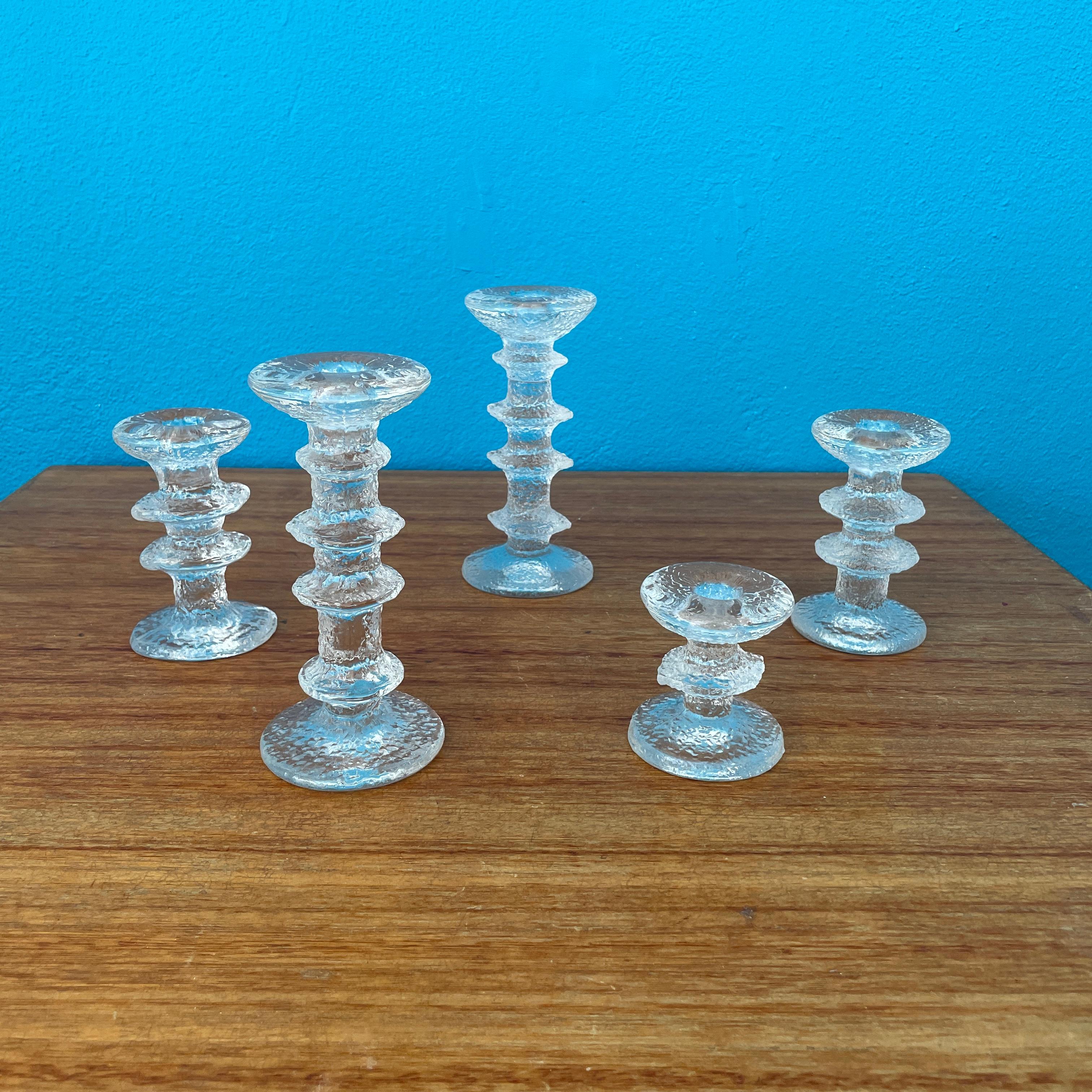 Festivo candleholders were designed by Timo Sarpaneva for Iittala in 1966. The striking glass objects feature an ice-like, textured design and come in various heights.

This set includes 5pcs candlesticks, all have a signature 