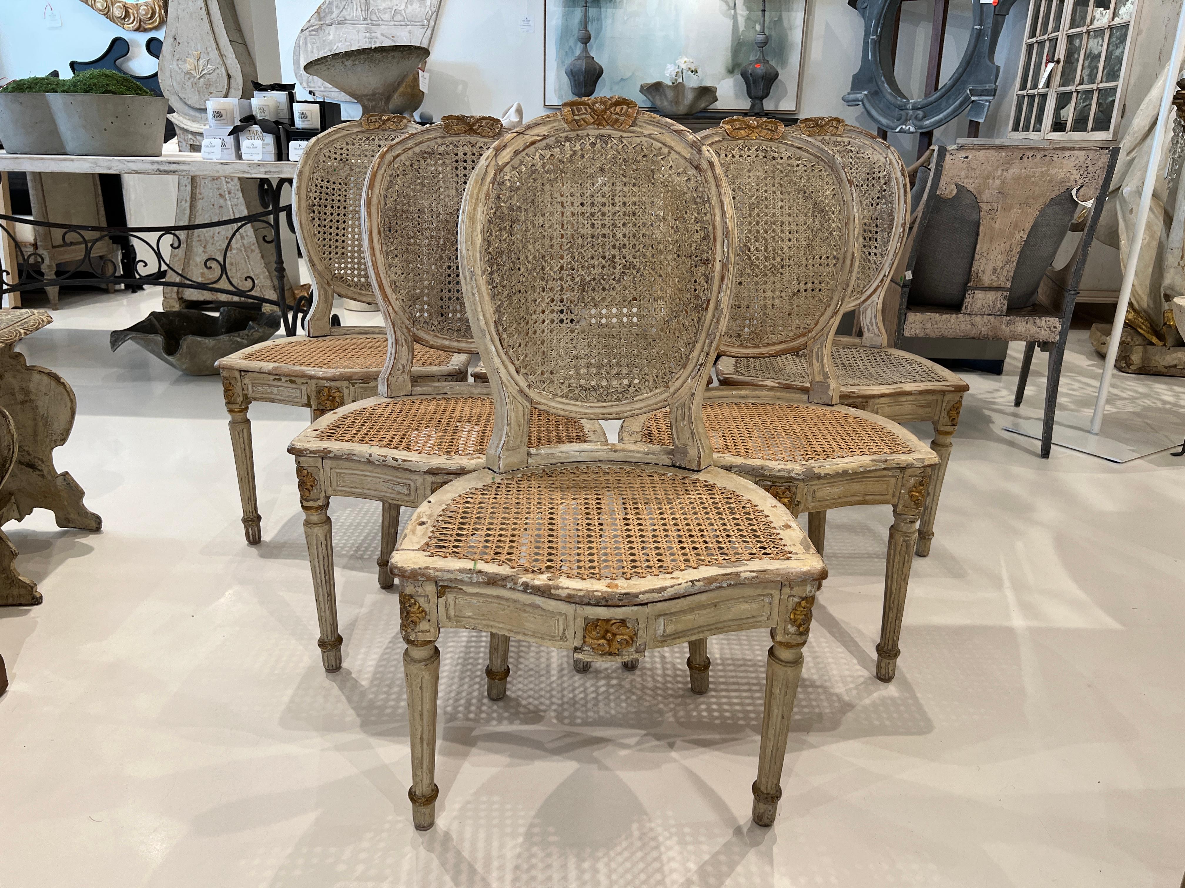 Set of 6 matching side chairs in carved and painted wood with caning on the backs and seats.