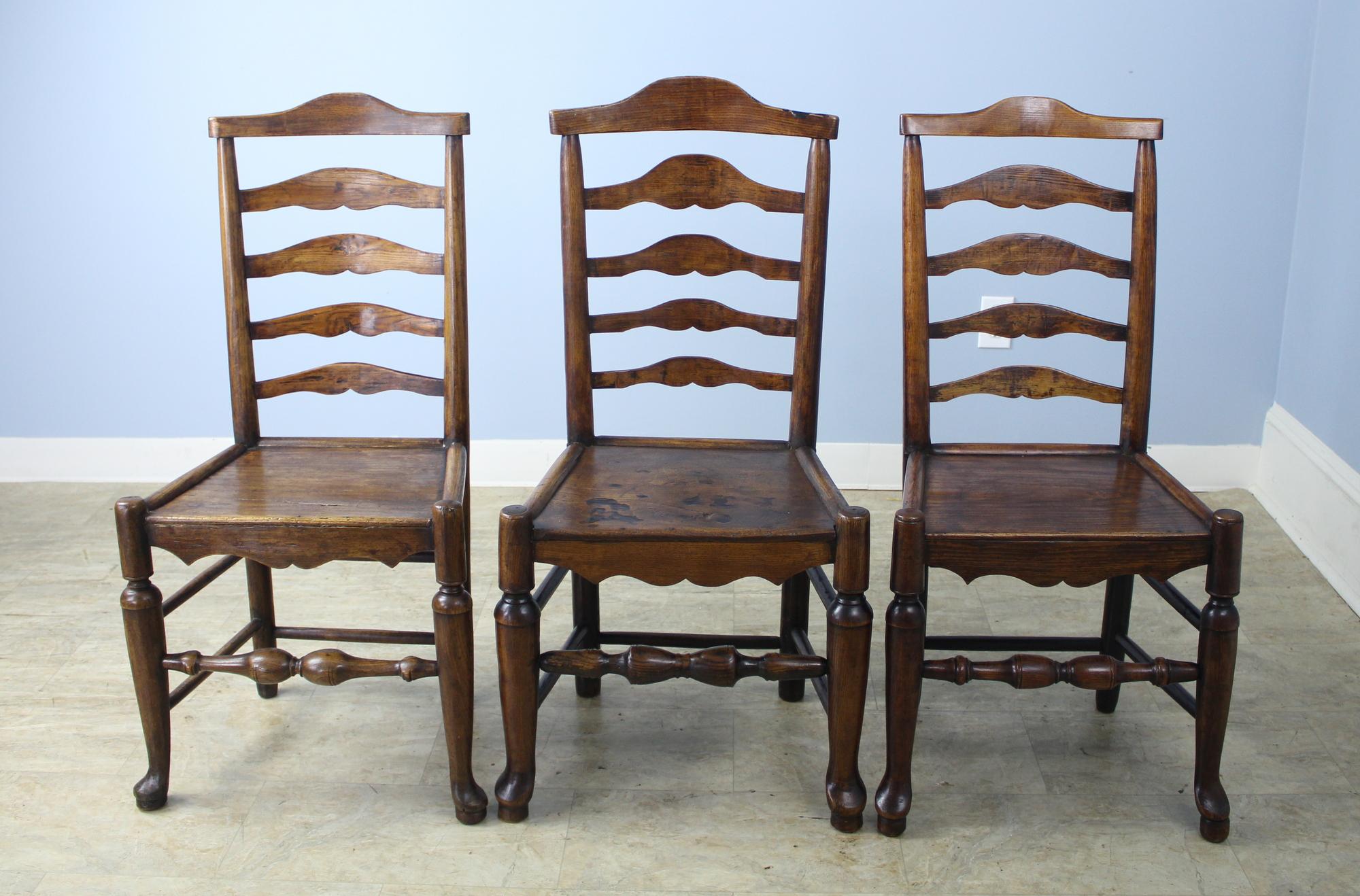 A splendid set of six handmade 18th century oak and ash dining chairs, with great patina and nice curved ladderbacks. Due to their age, each chair has slightly different wear patterns and profiles. See here a sampling of three of the set, and notice