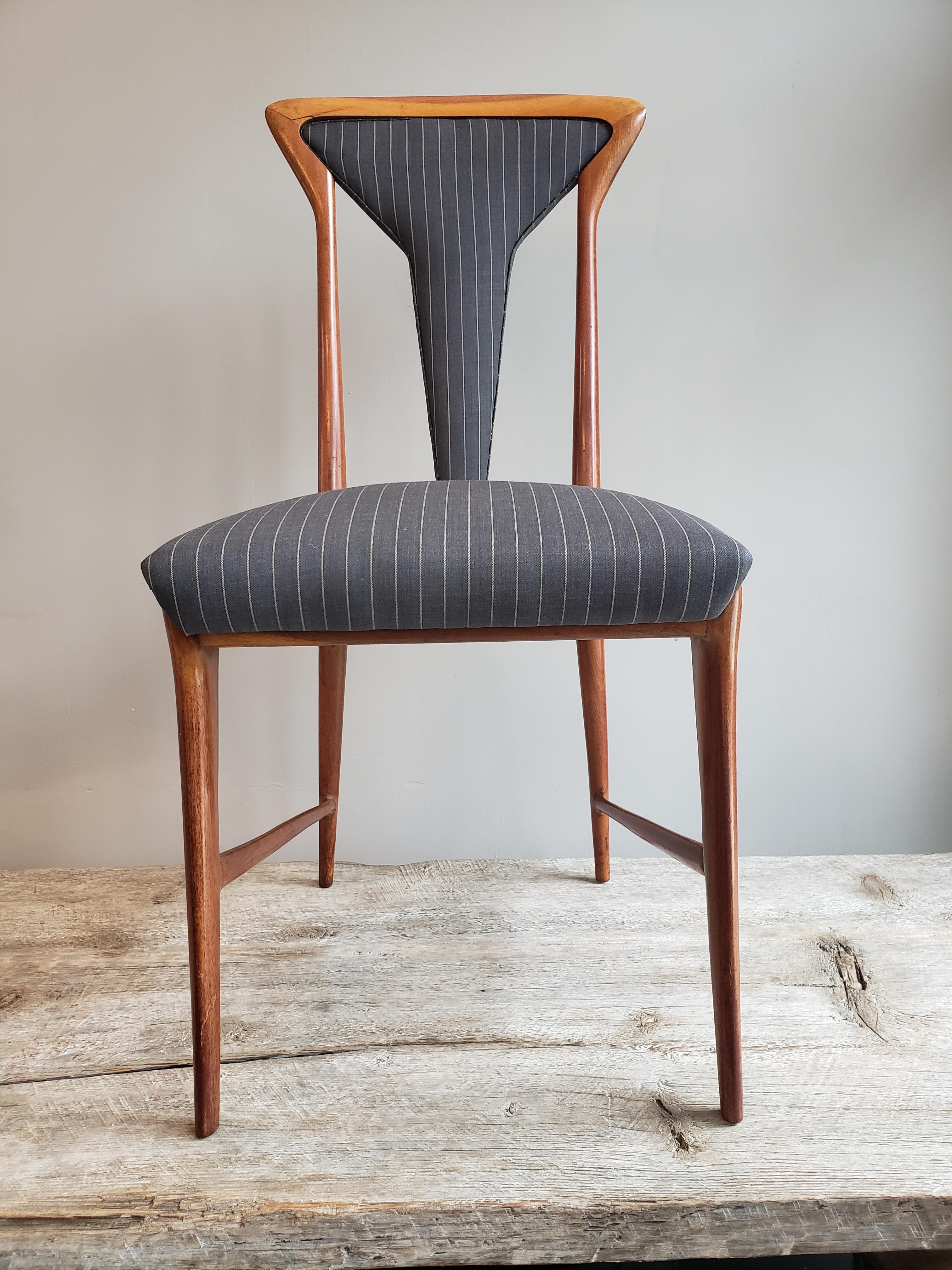 A set of 6 Mid-Century Modern upholstered dining chairs from Italy and designed by Carlo De Carli. Made out of walnut wood and upholstered in a sophisticated masculine gray and white pin striped fabric. Circa 1950's.
