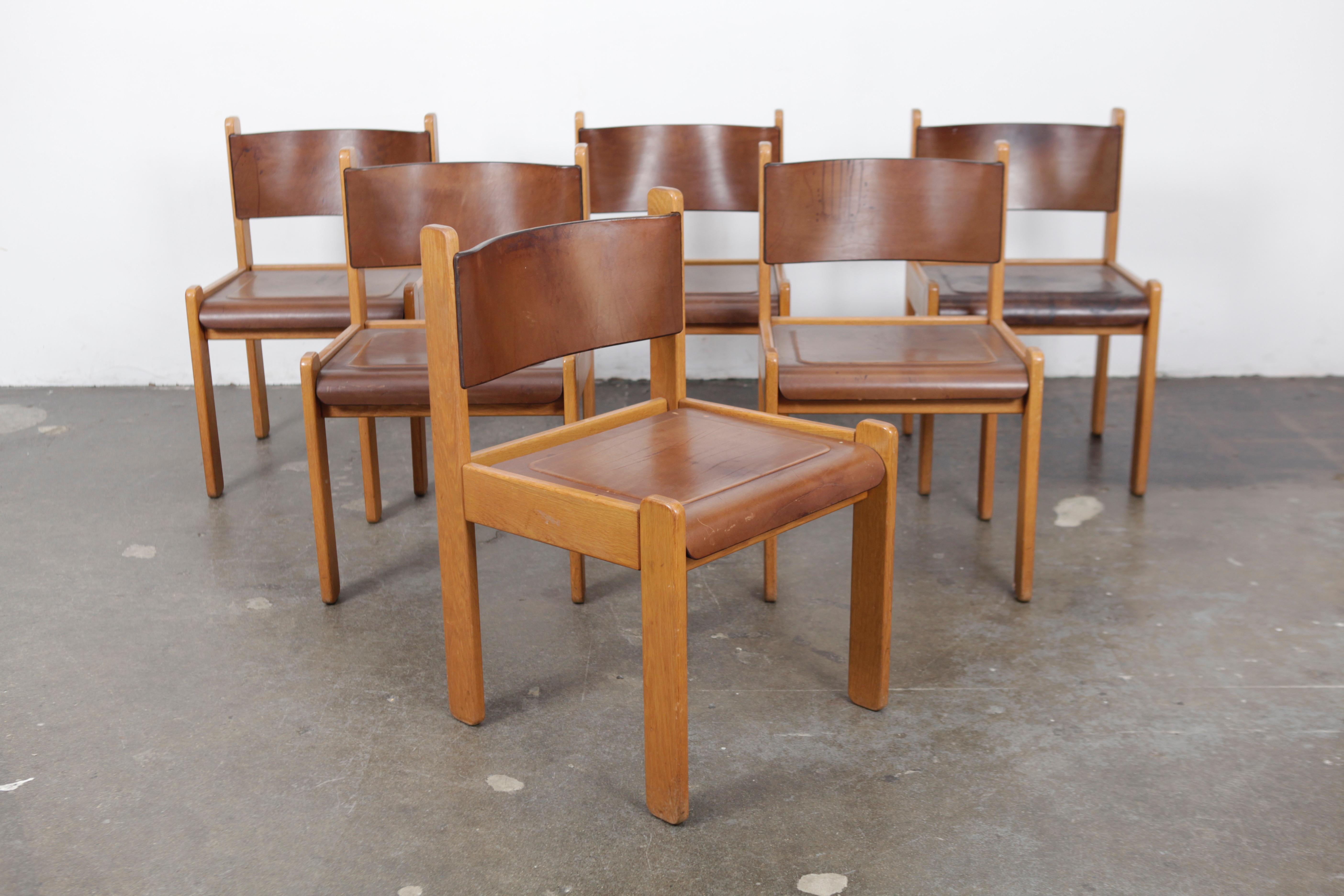 Set of 6 solid oak framed dining chairs with very unique bent leather and wood seats and backs, 
Italy, 1970s. The leather is actually the top and bottom layer in the bent ply seat, part of the plywood itself. Chairs are in original condition, not