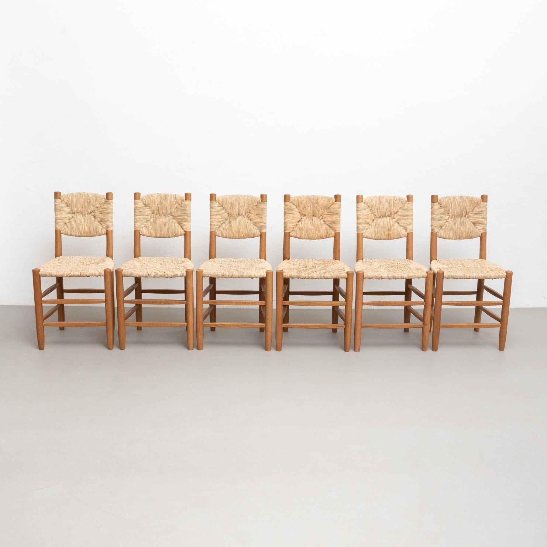 Chair designed in the style of Charlotte Perriand, made by unknown manufacturer.    Wood and rattan.    In good original condition, with minor wear consistent with age and use, preserving a beautiful patina.