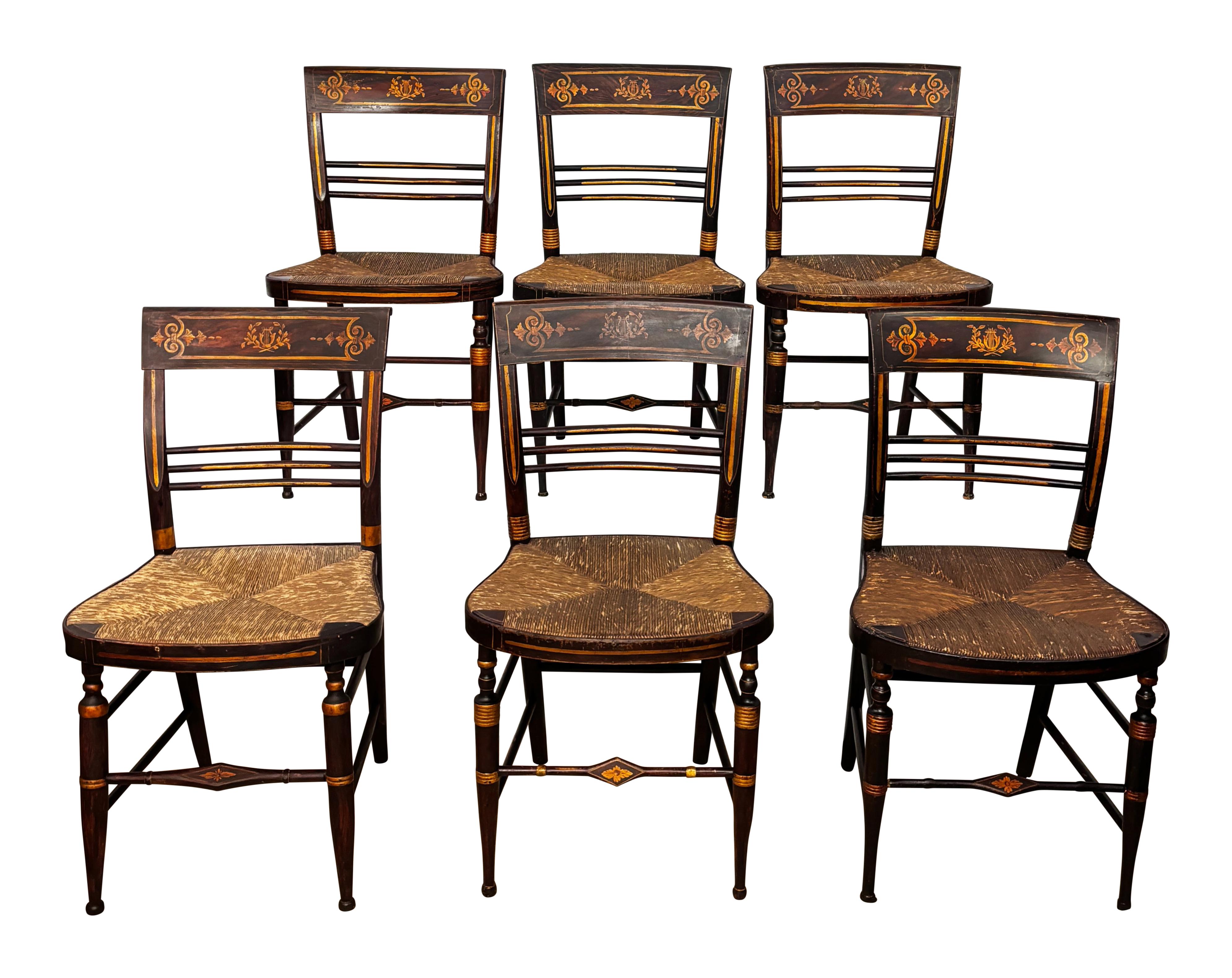 Ensemble de six chaises de style Hitchcock de la Nouvelle-Angleterre. Peint à la main / au pochoir et doré avec une patine profonde et riche due à des années d'usure. Les sièges sont en jonc tissé et sont en très bon état d'origine. 
Dans un état