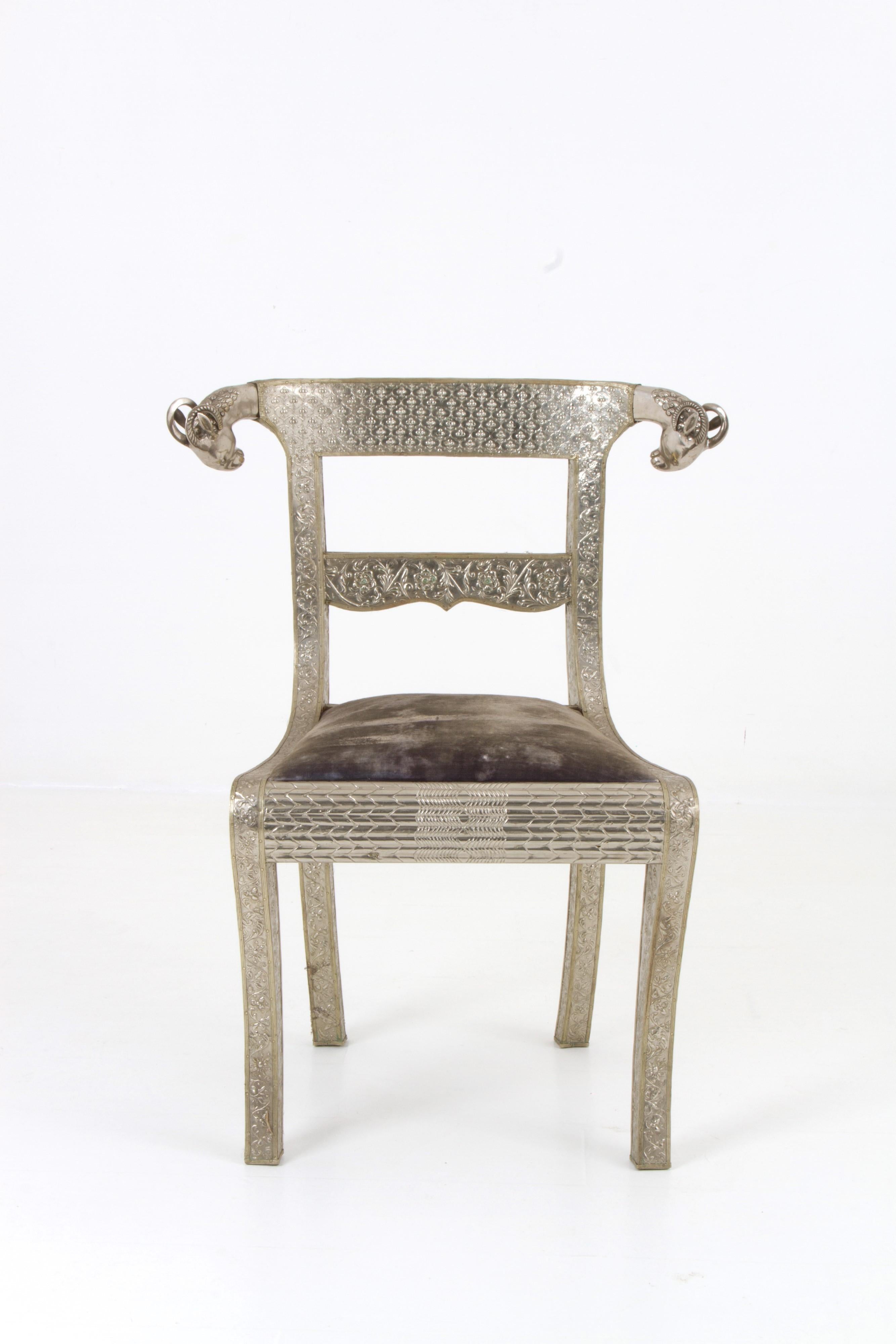 Juego de 6 sillas angloindígenas de época, de madera dura autóctona revestida de metal, decoradas con motivos florales y geométricos martillados y prensados, con cabezas de carnero niqueladas en las crestas y patas delanteras de sable
Altura: 34