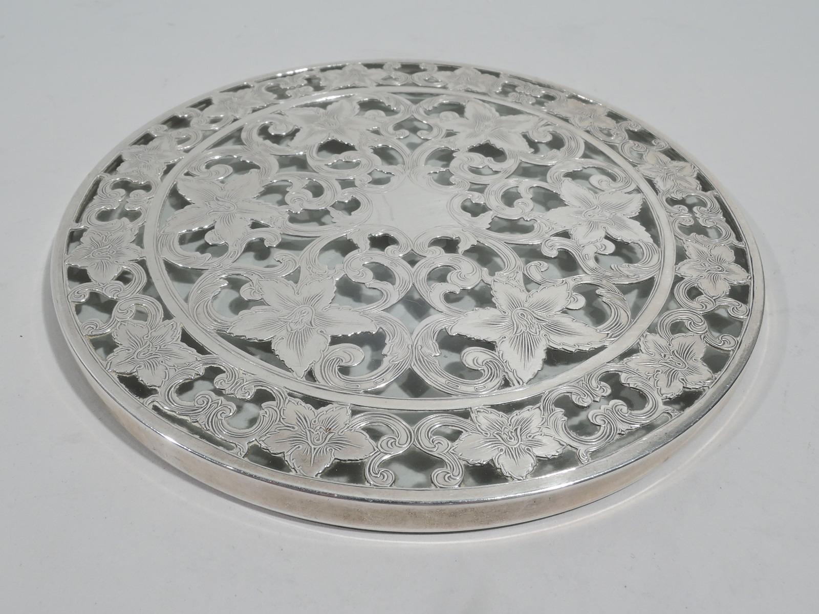 Set of 6 turn-of-the-century Art Nouveau glass trivets with engraved silver overlay. Made by Webster in North Attleboro. Each: Flat and circular; central 6-point star (vacant) surrounded by dense scrolls and flowers; border same. Glass is clear.