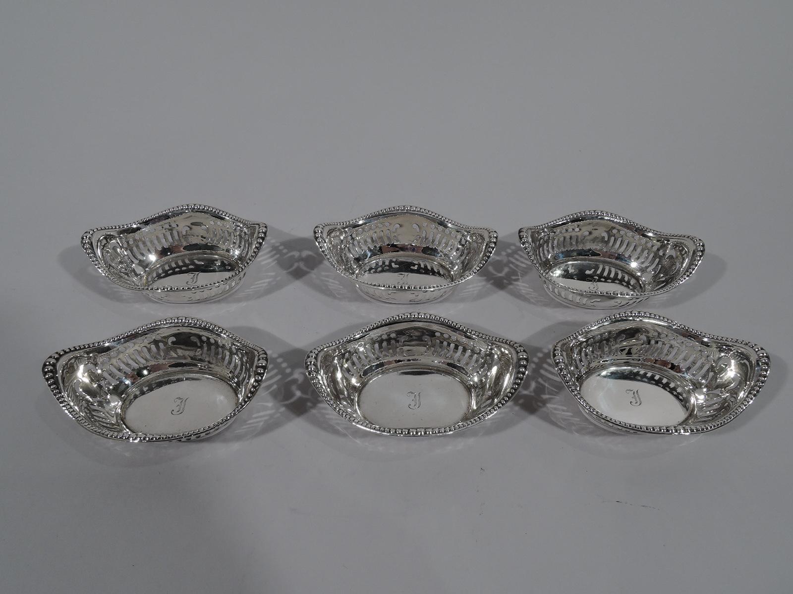 Set of 6 Edwardian sterling silver nut dishes. Made by Gorham in Providence, circa 1910. Each: Boat form with solid oval well. Sides have pierced geometric ornament. Rim wavy and beaded. Single-letter script monogram engraved in well. Fully marked