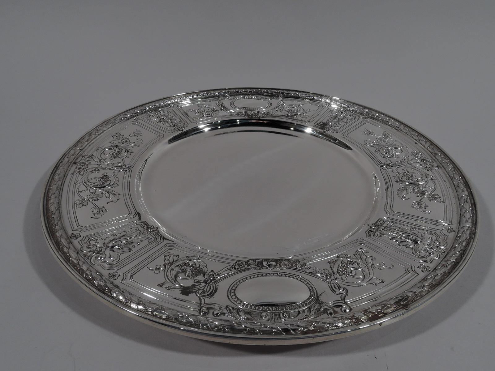 Set of 6 Maintenon sterling silver dinner plates. Made by Gorham in Providence in 1928. Each: Deep and plain well. Wide shoulder with chased leafy-scrollwork and flowers spilling over curvilinear frames. Two beaded oval frames (vacant). Imbricated