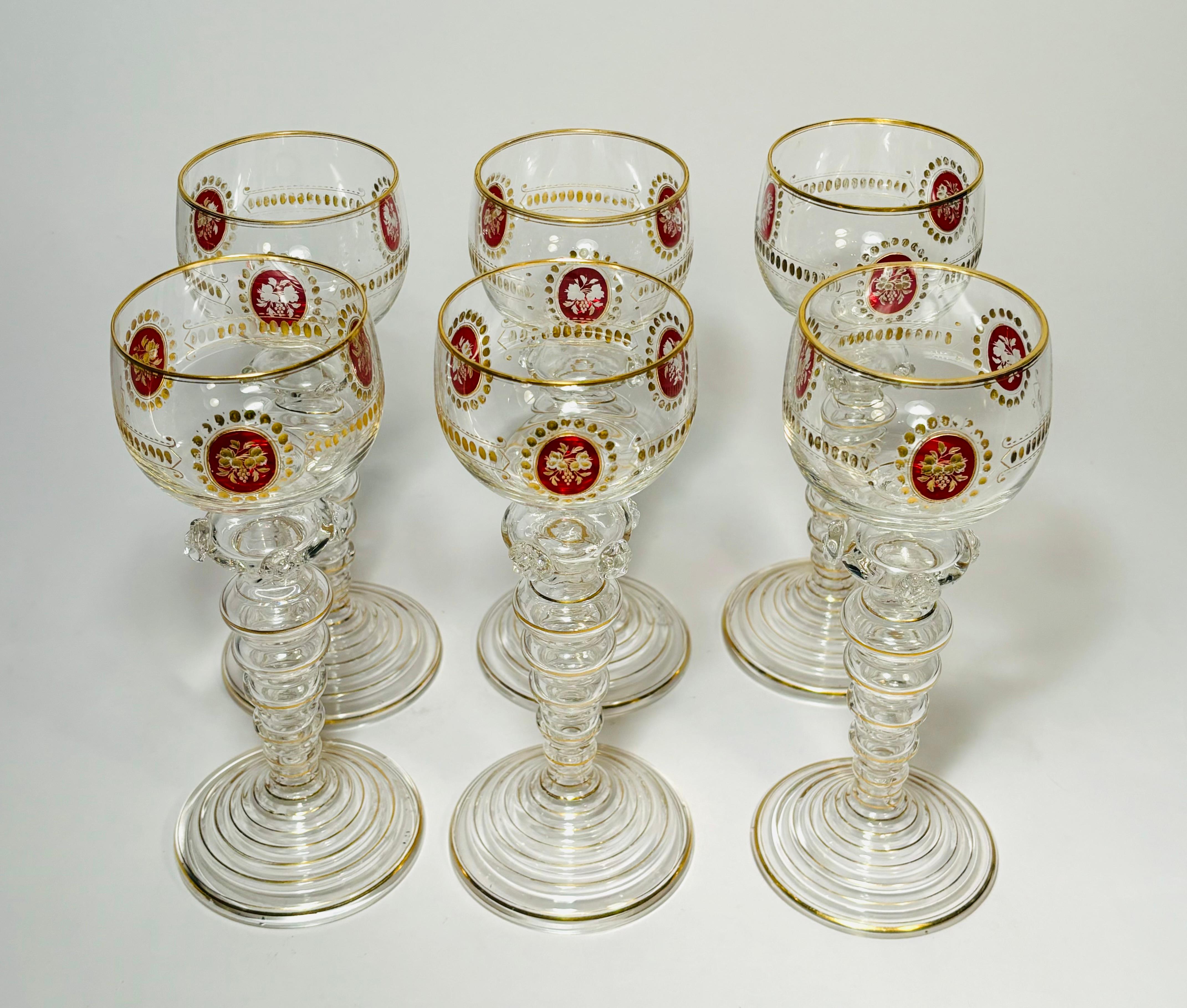 An elegant set of white wine glasses by one of our favorite Gilded Age Crystal Companies, Moser. These feature an uniquely blown shaped stem with added embellishments. The bowls have a ruby cartouche with hand cut and gilded accents. In very good