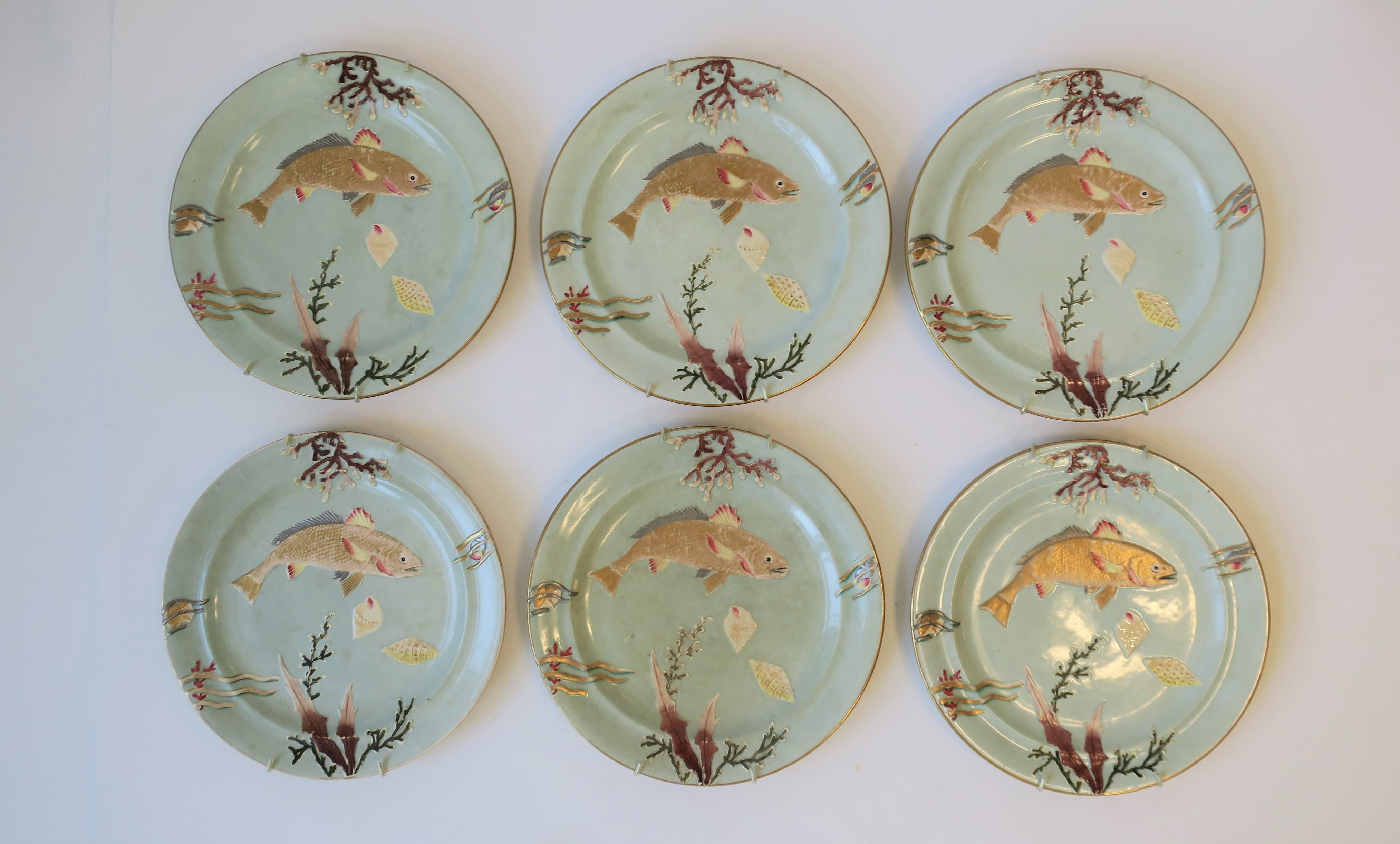 A very beautiful set of 6 antique dinner or lunch plates with gold bass fish and a coral seashell/sea shell raised relief design, circa early 20th century. Plates also come with six wall brackets for hanging if so desired. Colors include: seafoam