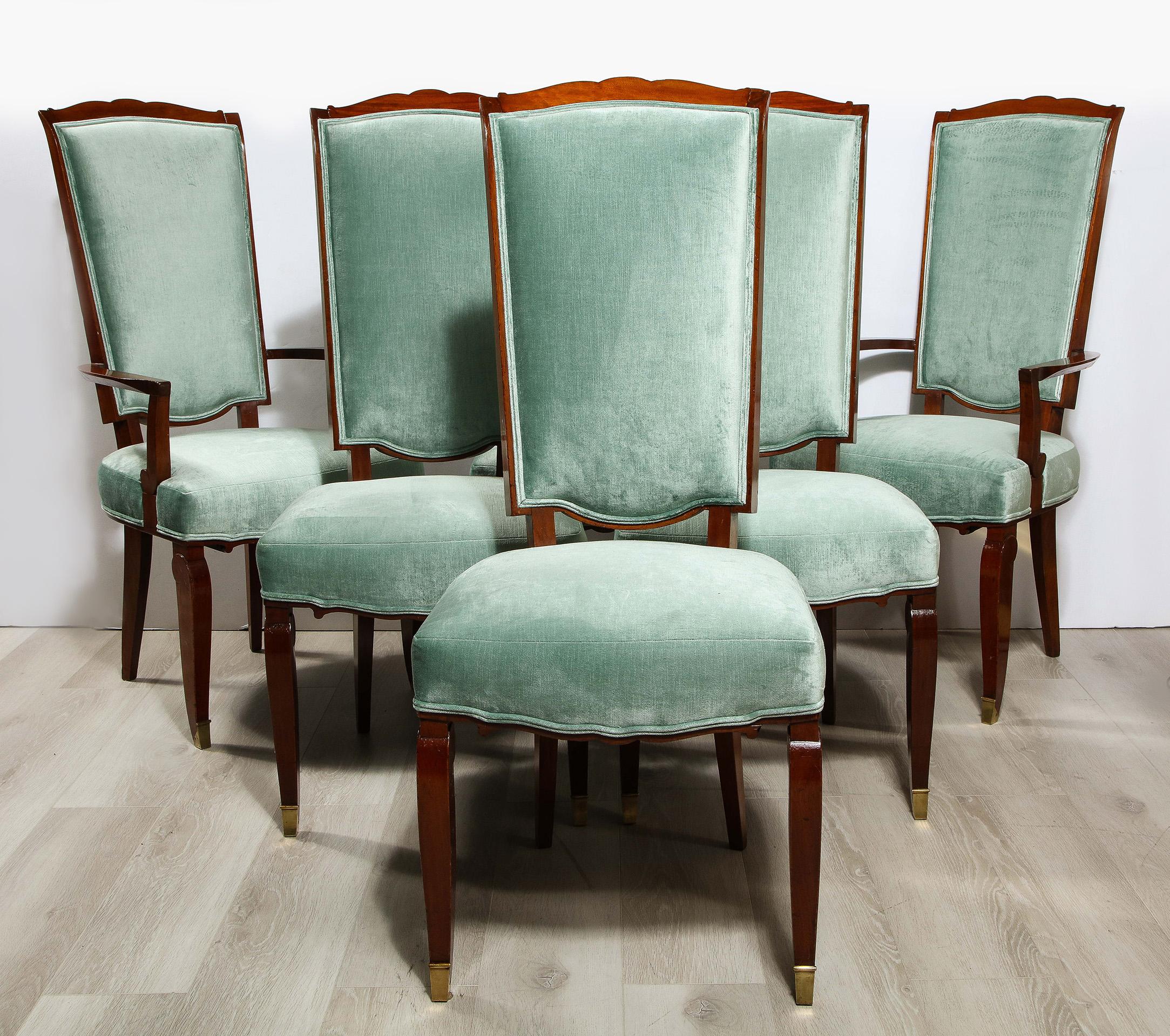 An exceptional set of six mahogany dining chairs, comprising four side chairs and two armchairs. Each with a serpentine outlined back. The arms being out swept, all having upholstered seat and serpentine rail, with stylized scroll legs with gilt